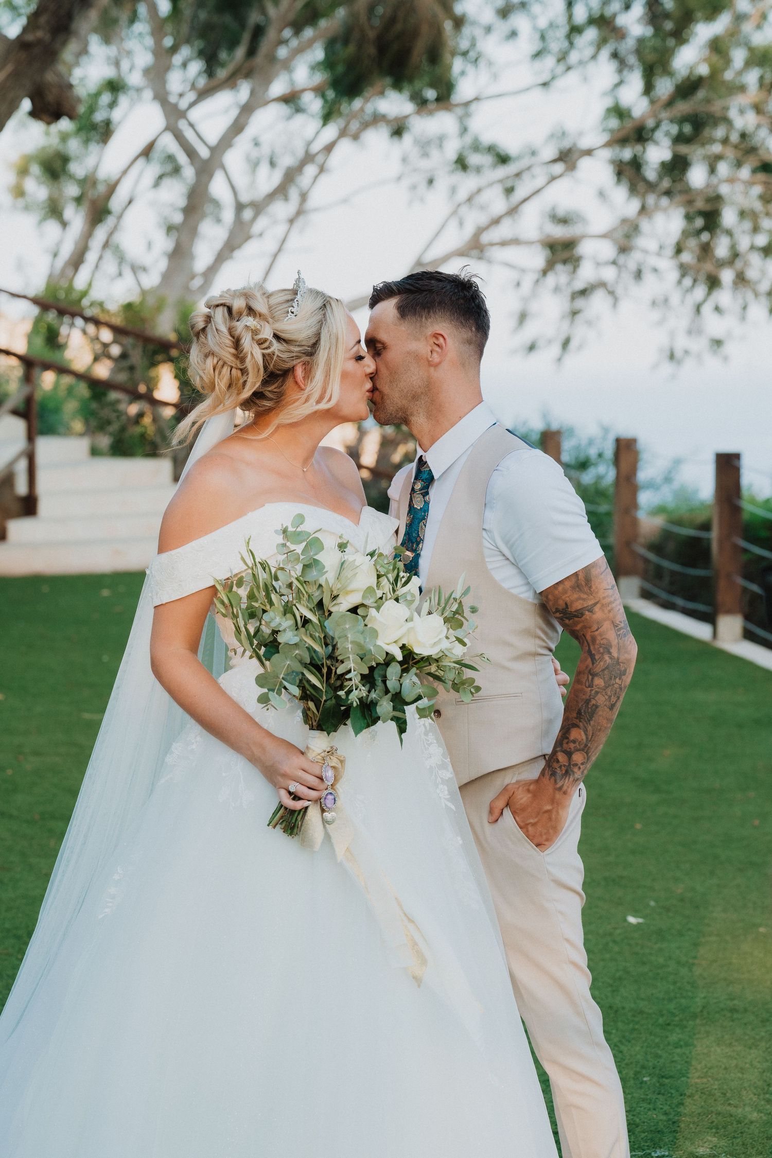 Garden wedding portrait with eucalyptus bouquet and romantic kiss.