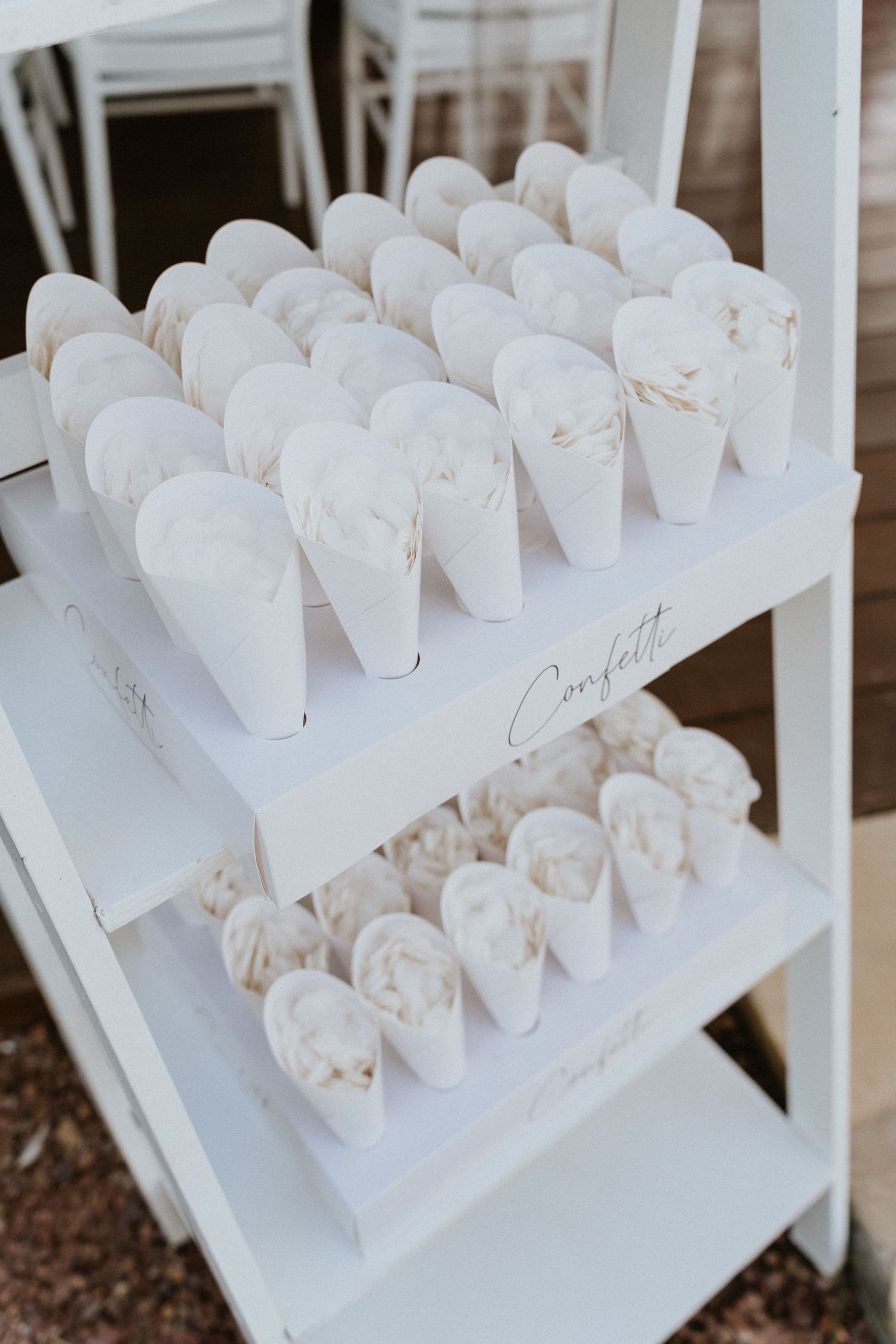 White confetti cones elegantly displayed on tiered shelves at a wedding reception.