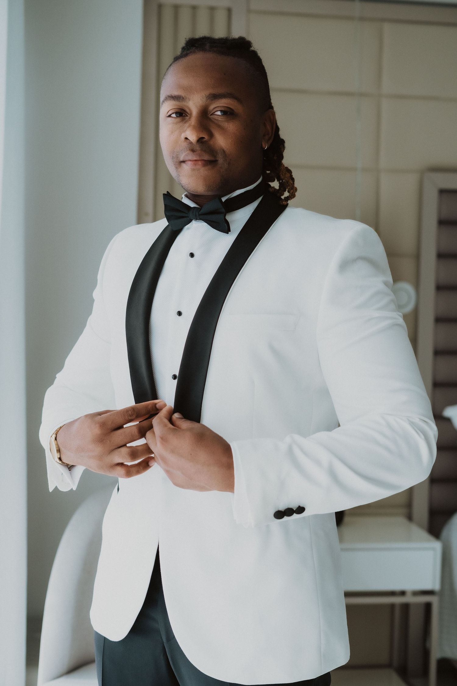 A person poses in an elegant white tuxedo jacket with black shawl lapels.