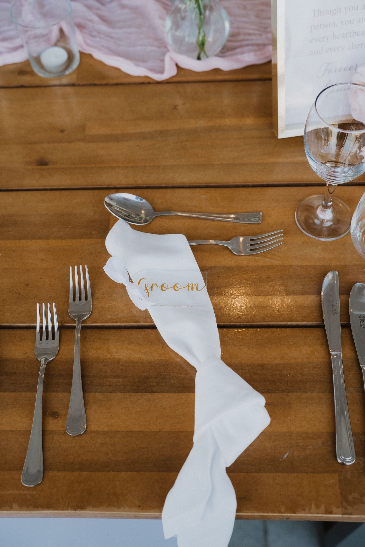 Place settings on a rustic wooden table feature white napkins and silverware arranged in a neat row.