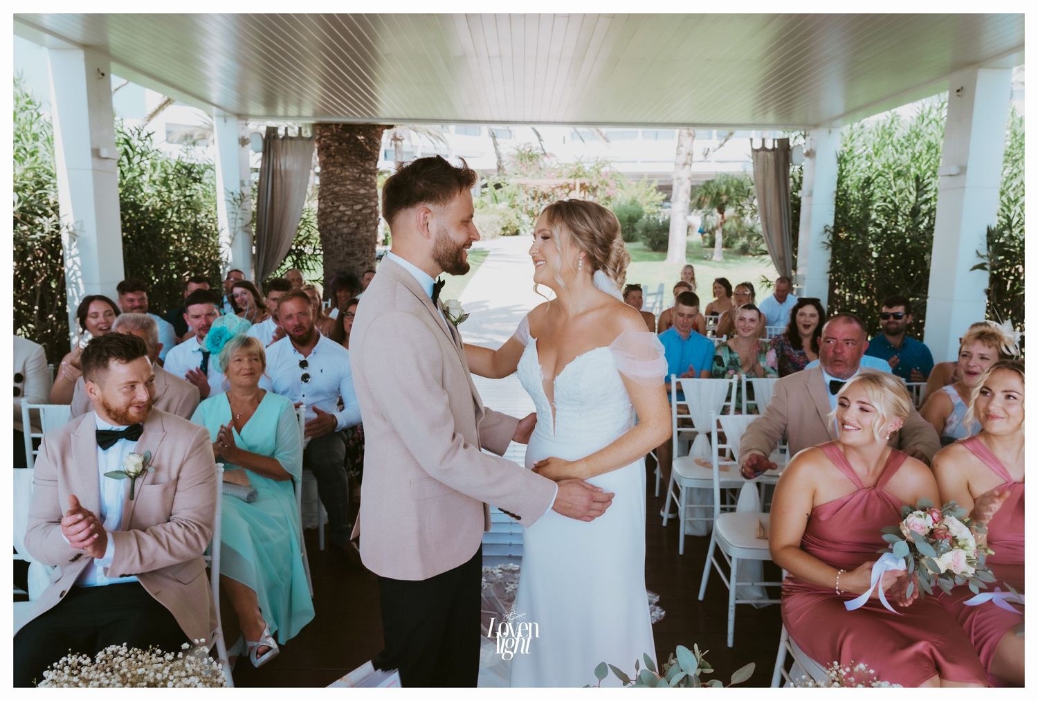 Wedding celebration in an outdoor pavilion with guests wearing shades of blue and coral.