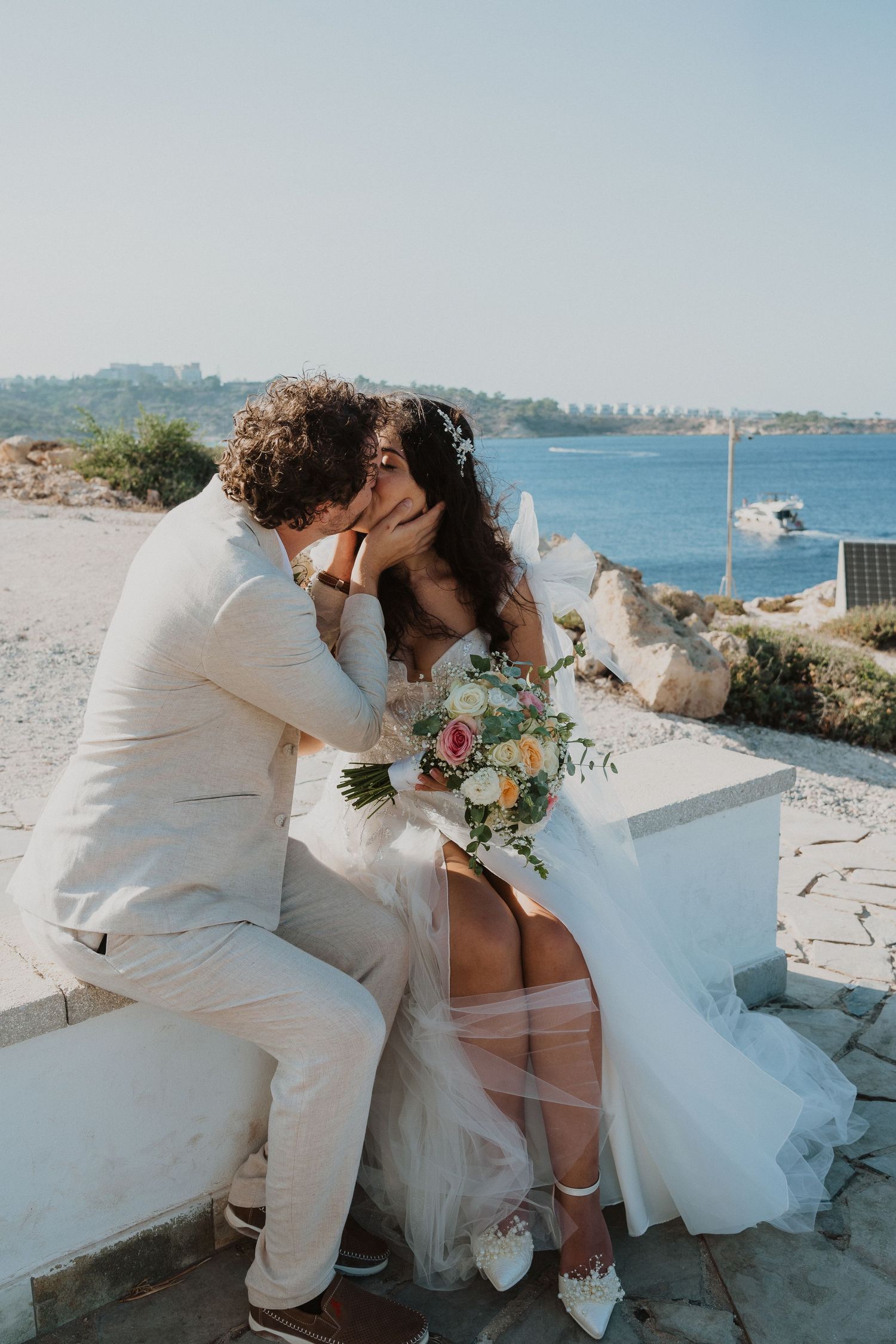 A romantic wedding moment captured on a white stone terrace overlooking the sea.