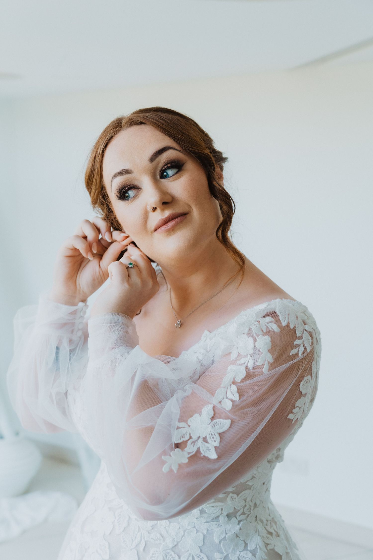 Portrait of bride holding white and pink rose bouquet with delicate makeup and updo hairstyle.