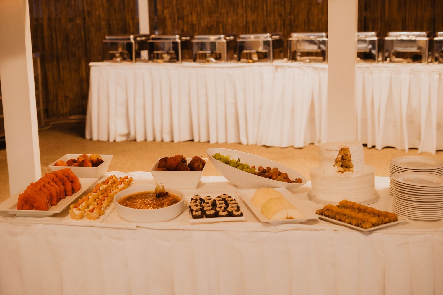 Wedding reception buffet table with white linens and various appetizers and dishes.