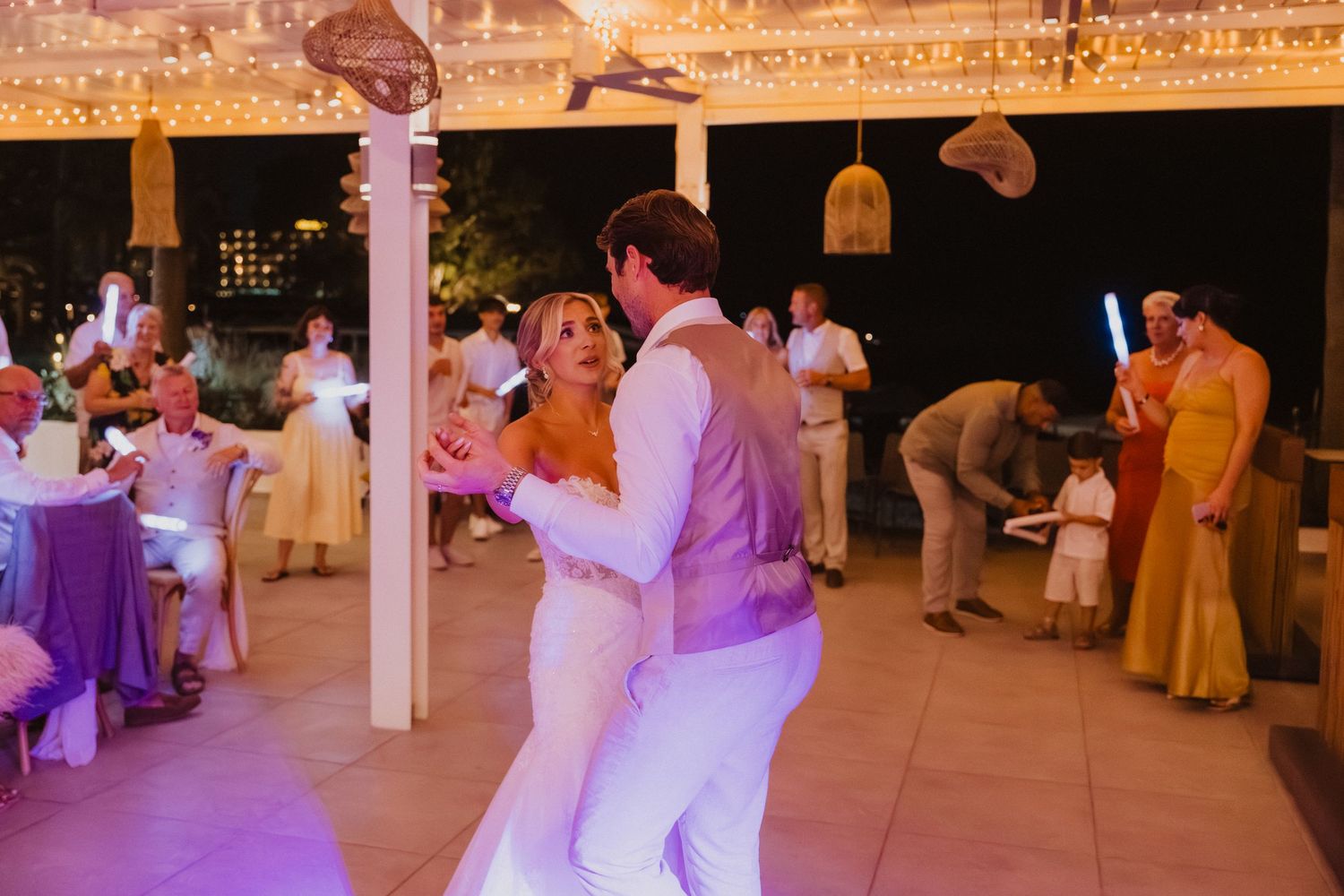 Wedding reception venue decorated with warm lighting and guests dancing on the dance floor.