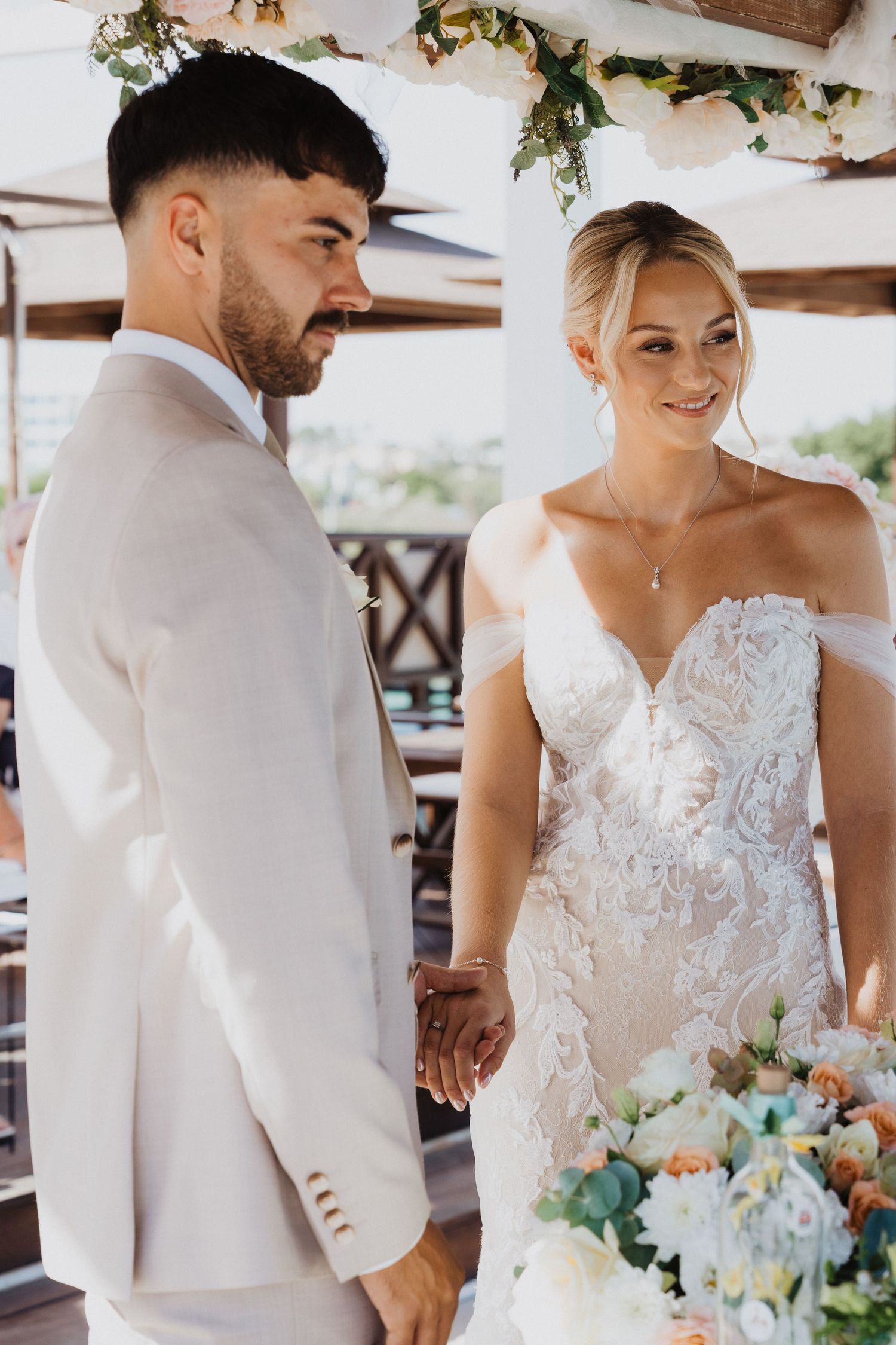 A couple shares a moment during their beachfront wedding ceremony with elegant floral decor.