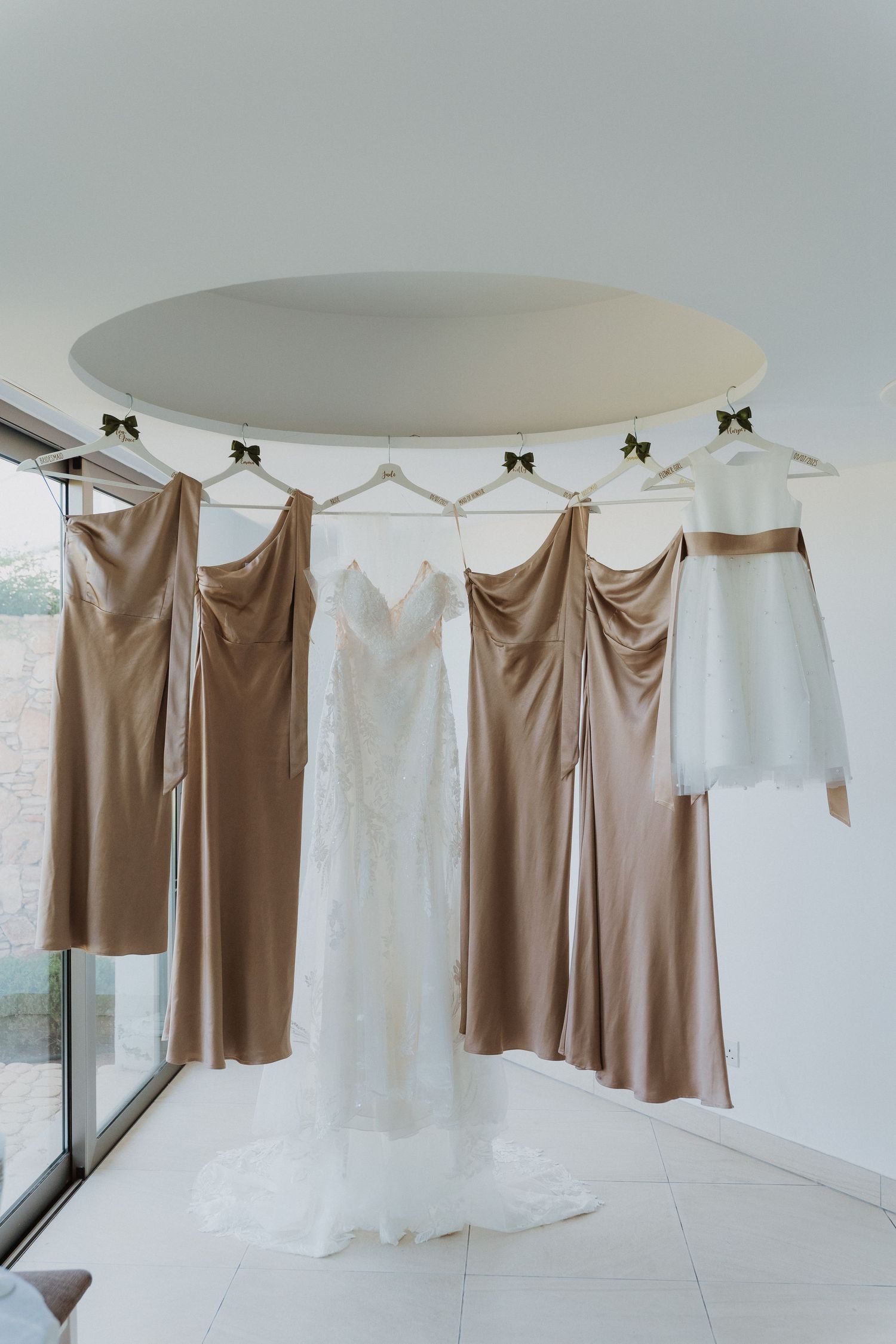 Brown and white clothing pieces hang on a circular clothing rack in a minimalist white interior space.
