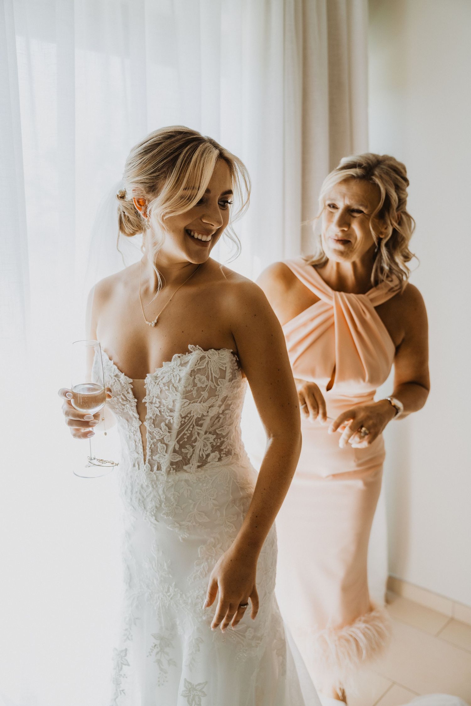 Series of photos showing the final adjustments of a strapless lace wedding gown.
