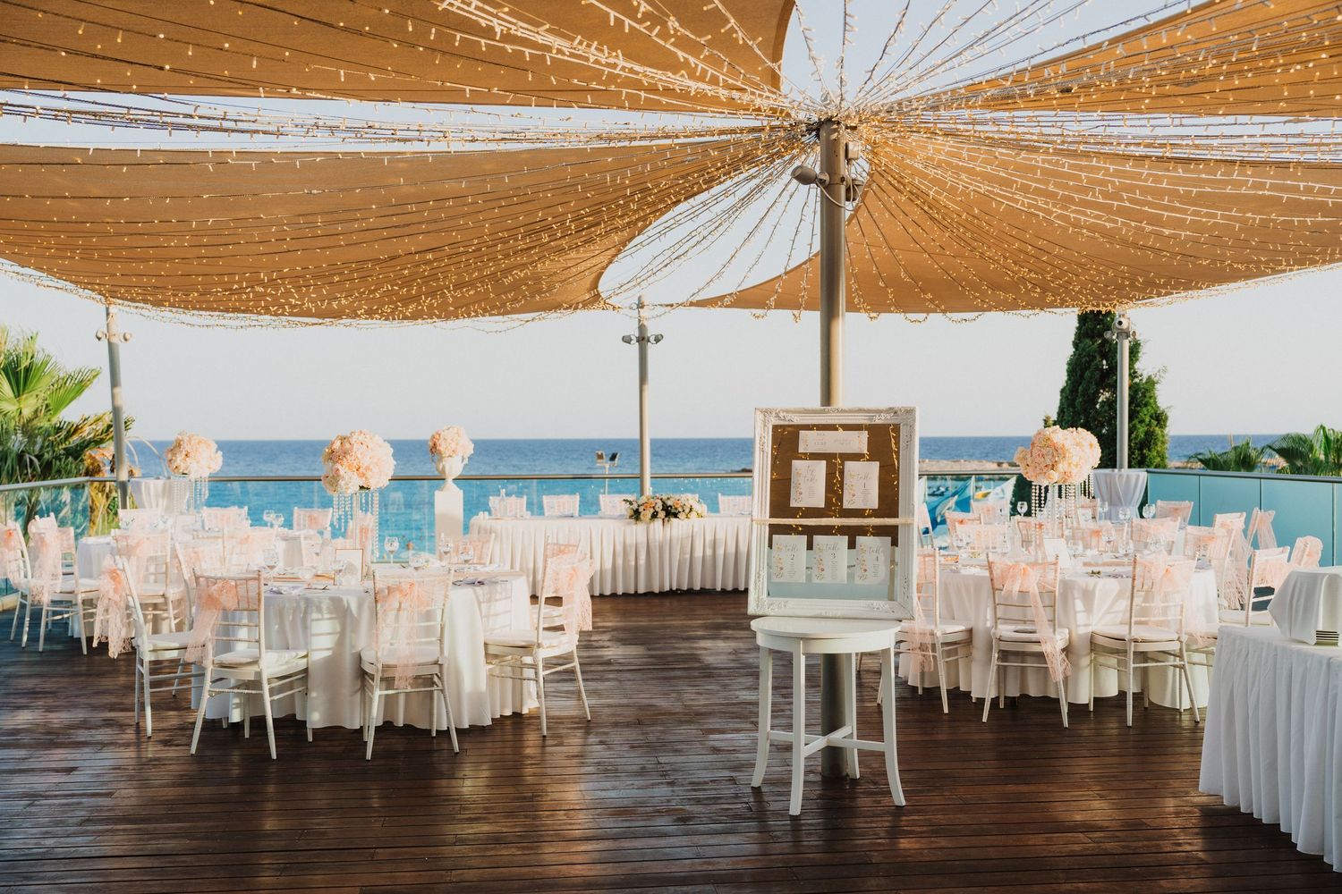 Wedding reception venue with wooden floors and gold draped ceiling with string lights.
