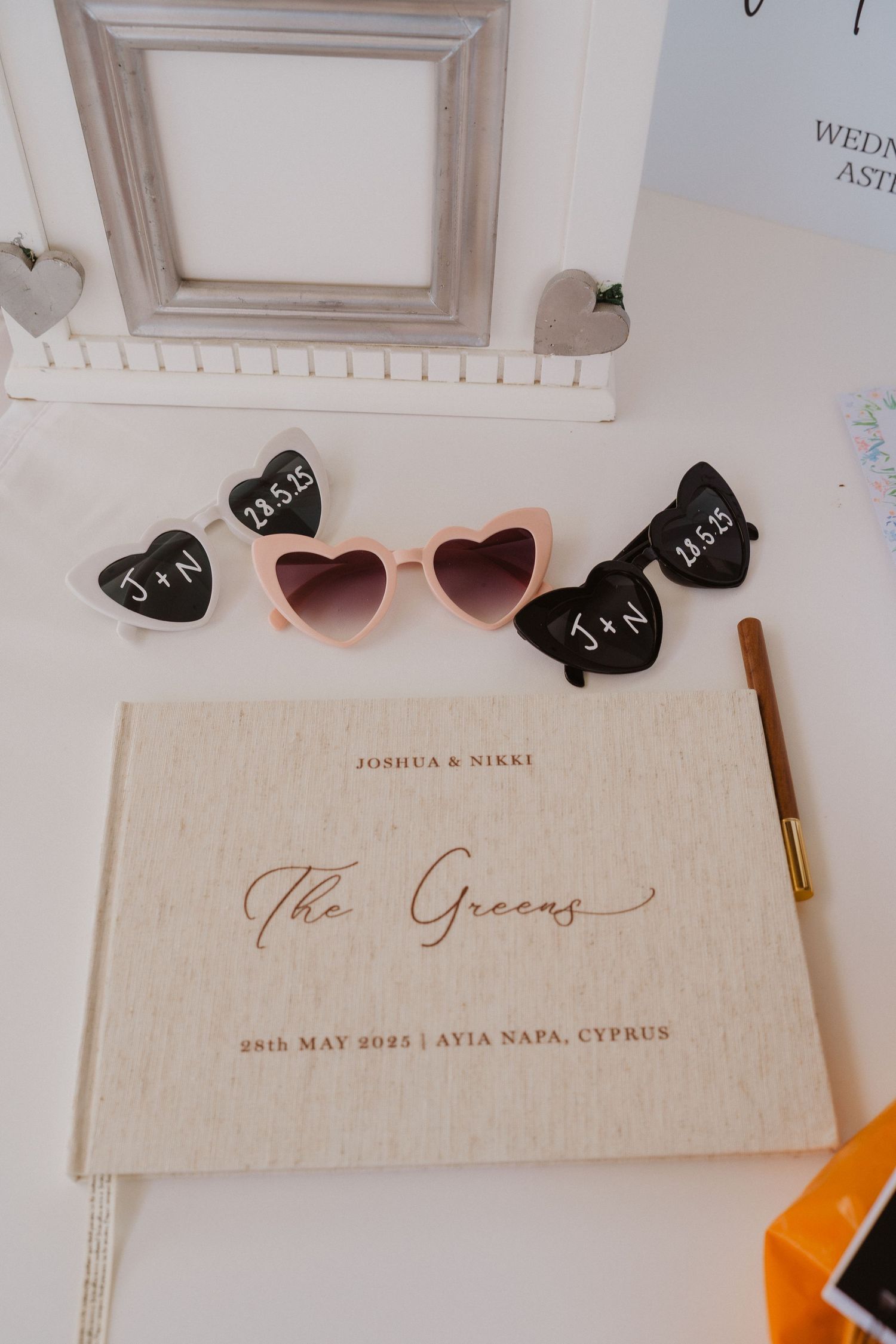 Close-up view of elegant wedding stationery with sunglasses and decorative elements on a light colored surface.