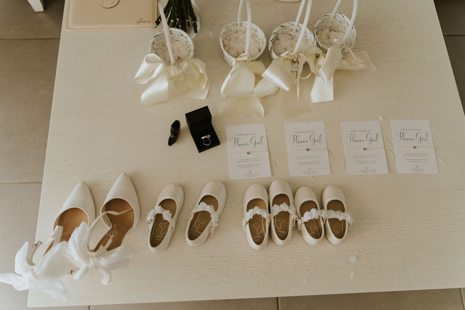Row of white dress shoes and name cards arranged neatly on a light surface.