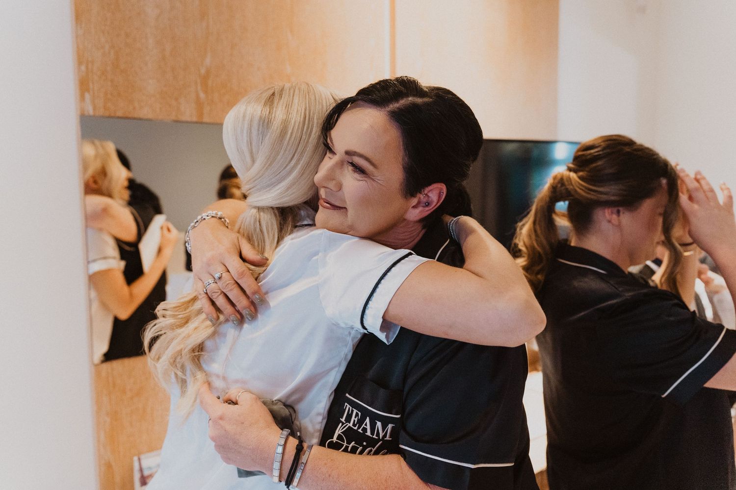 Wedding party members share emotional embraces and hugs during preparation time.