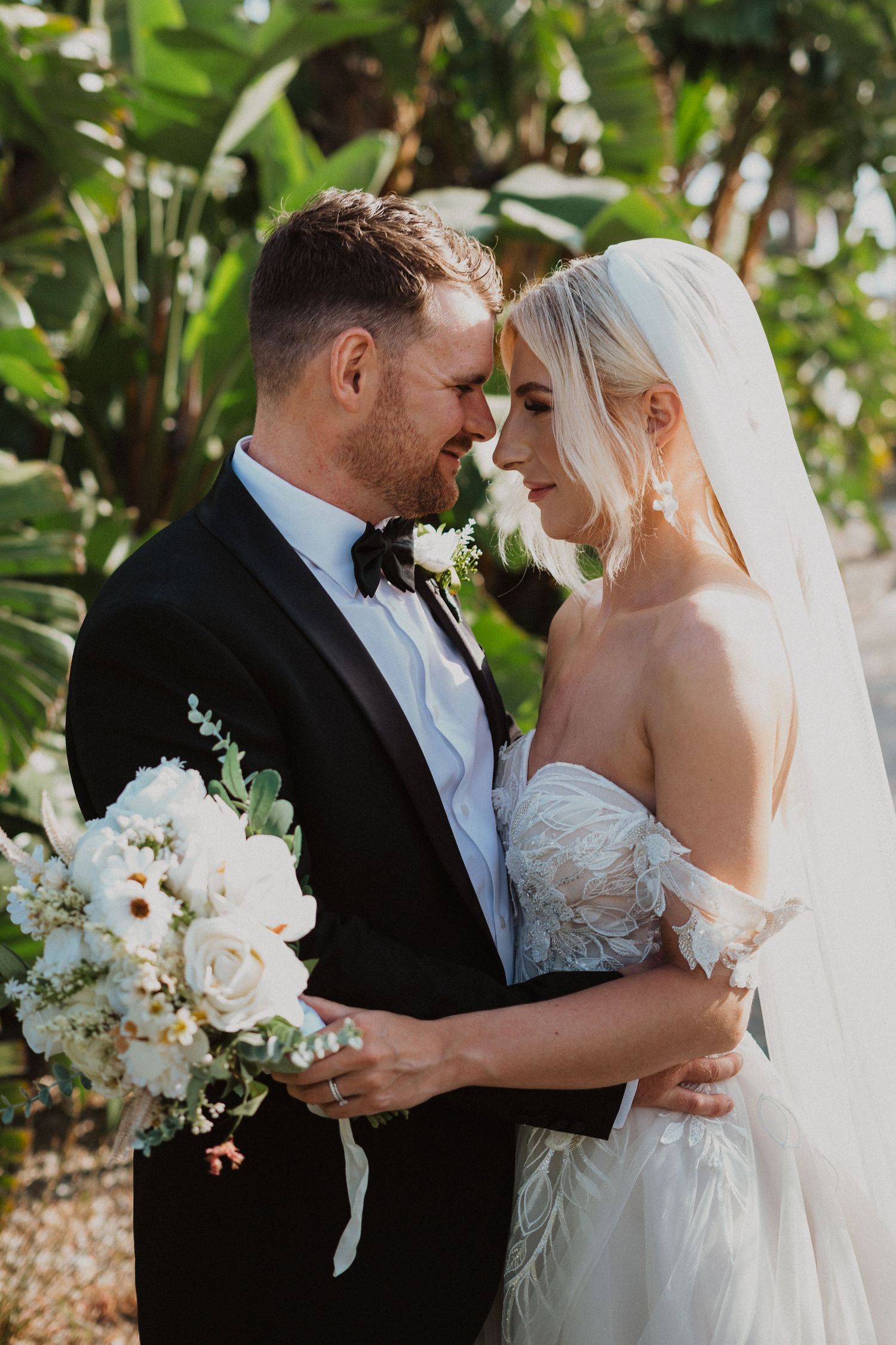 An intimate wedding moment captured in a garden with white roses and greenery.