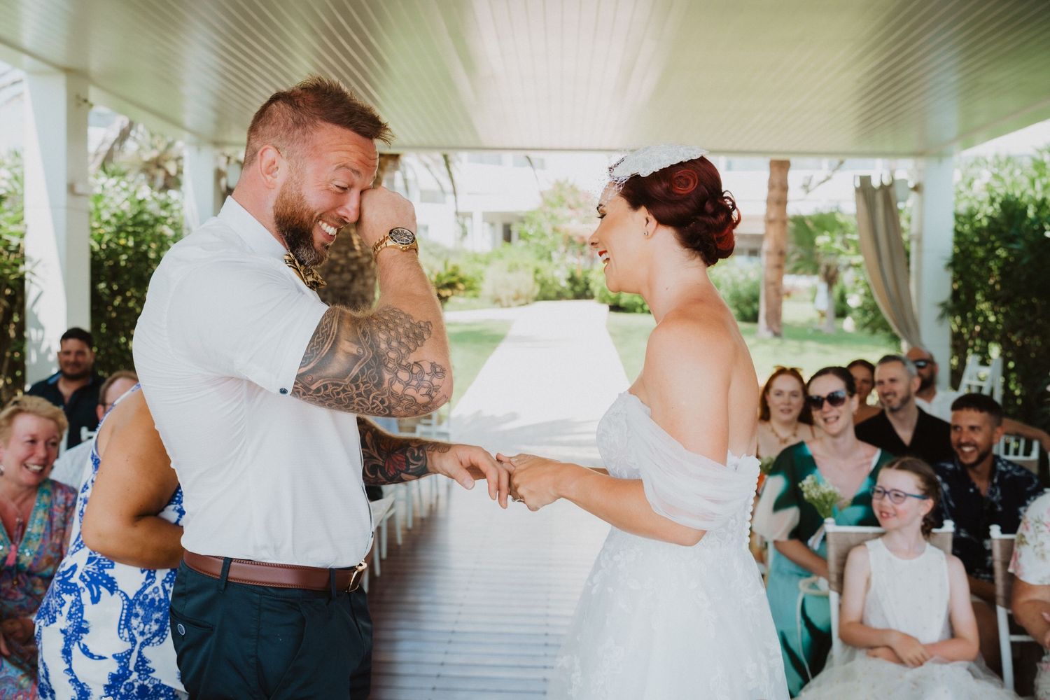 Emotional wedding ceremony moment under covered outdoor pavilion.