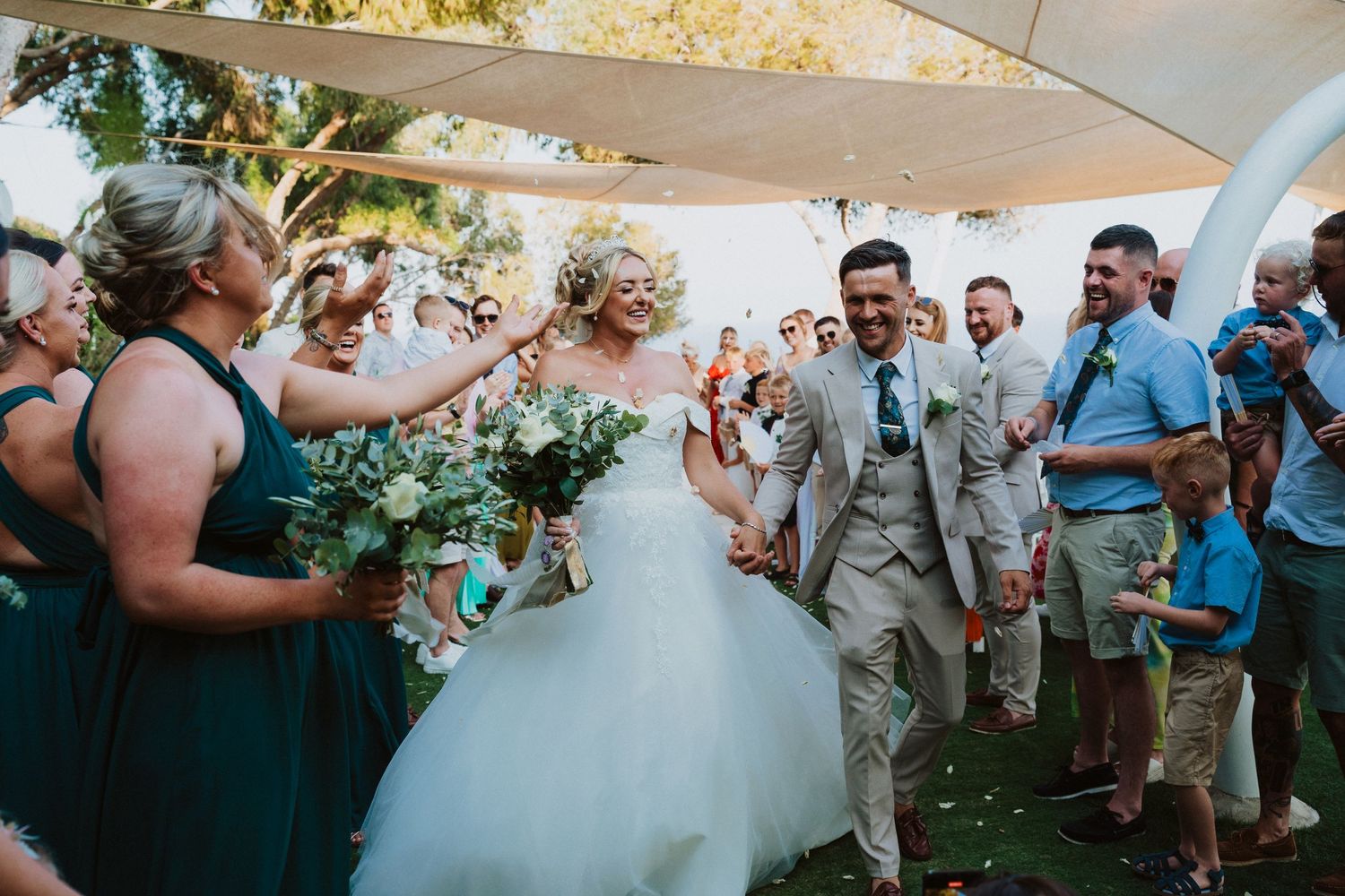 Wedding celebration under outdoor canopy with guests cheering the newlyweds.