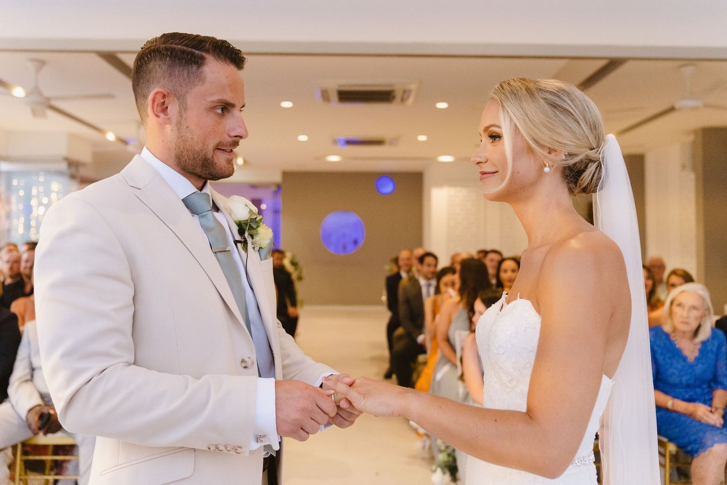 An intimate moment during wedding vows with purple accent lighting in an indoor ceremony space.