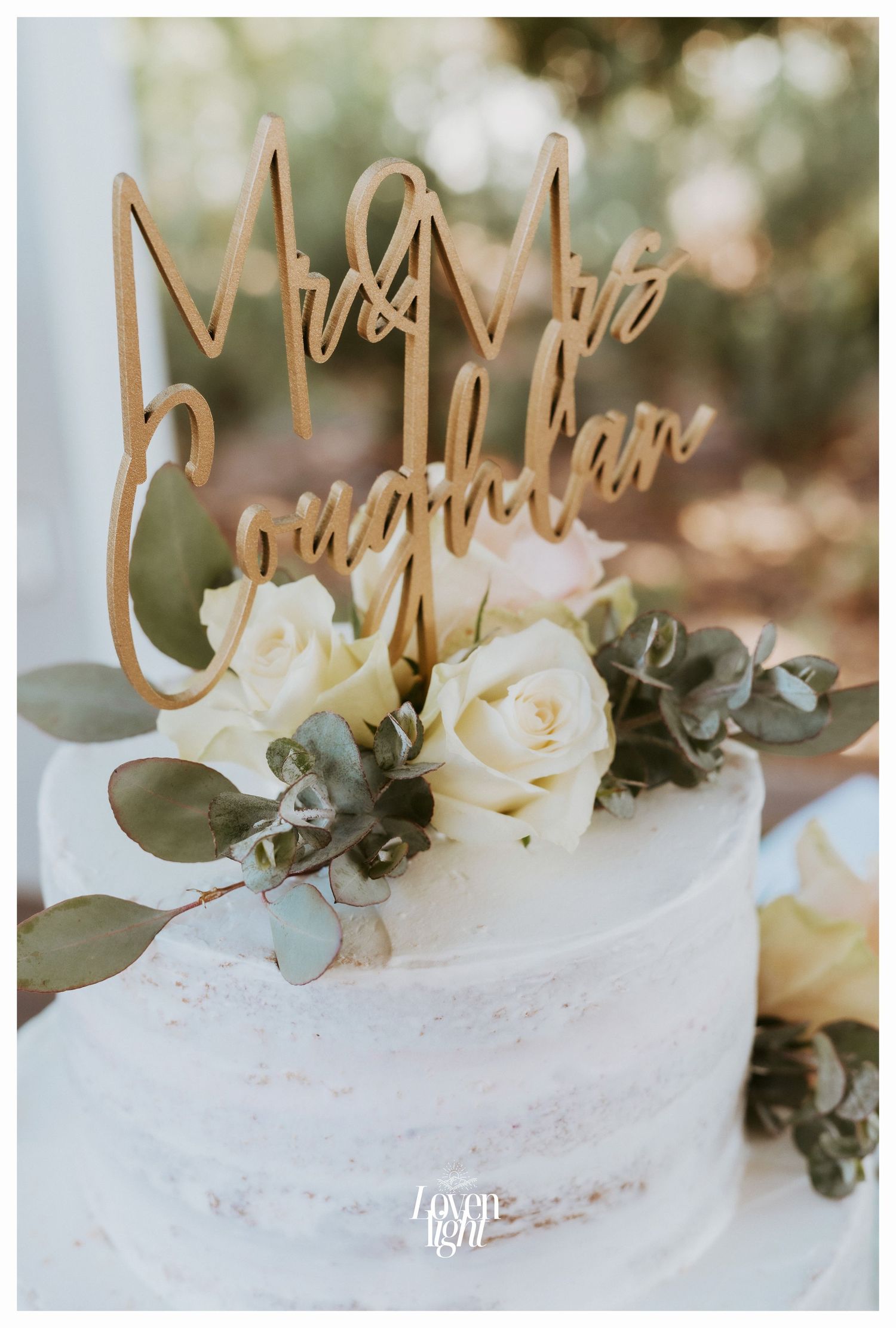 Close-up of wedding cake topper with white roses and eucalyptus decoration.