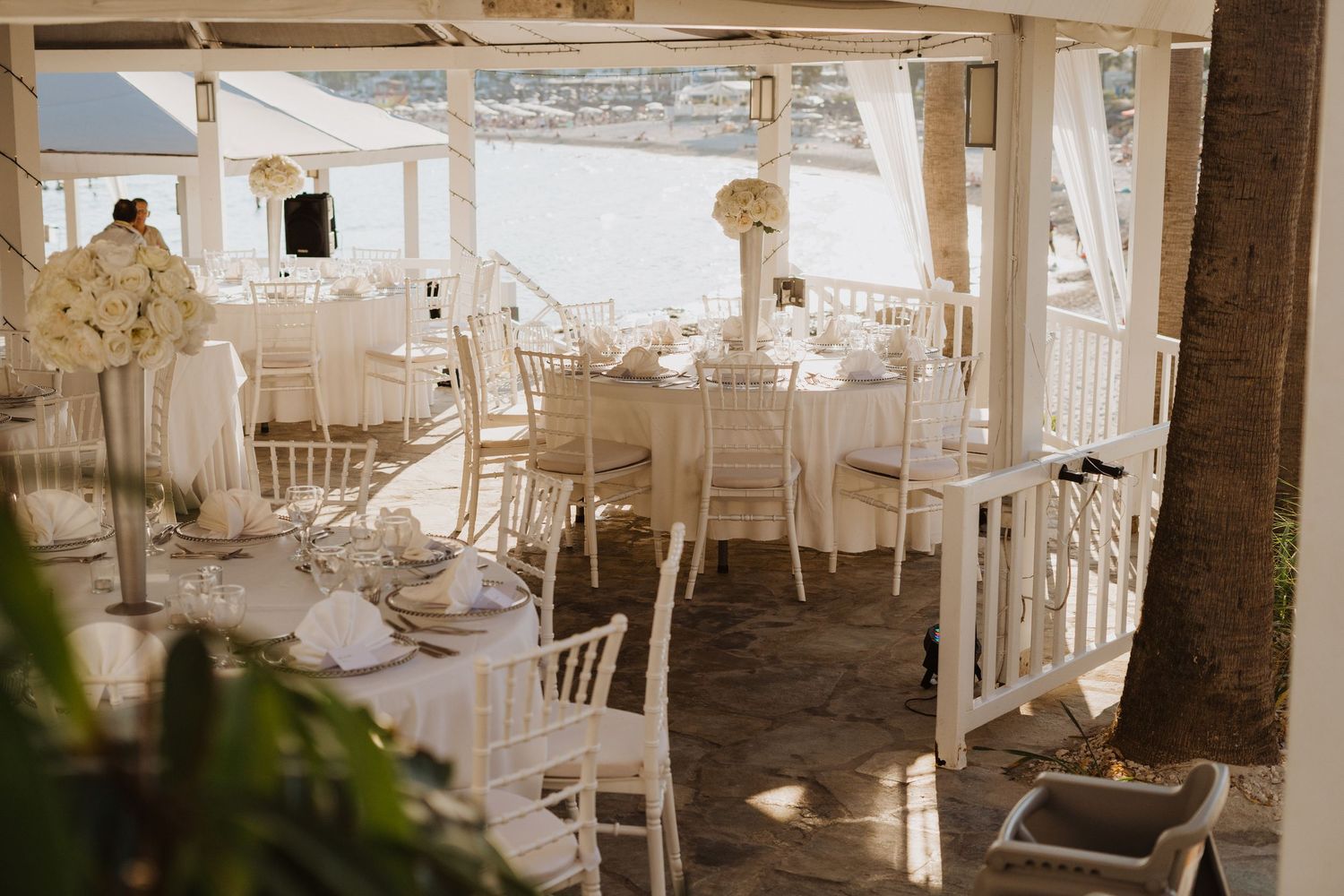 White Chiavari chairs line long reception tables in an airy wedding venue with natural lighting.