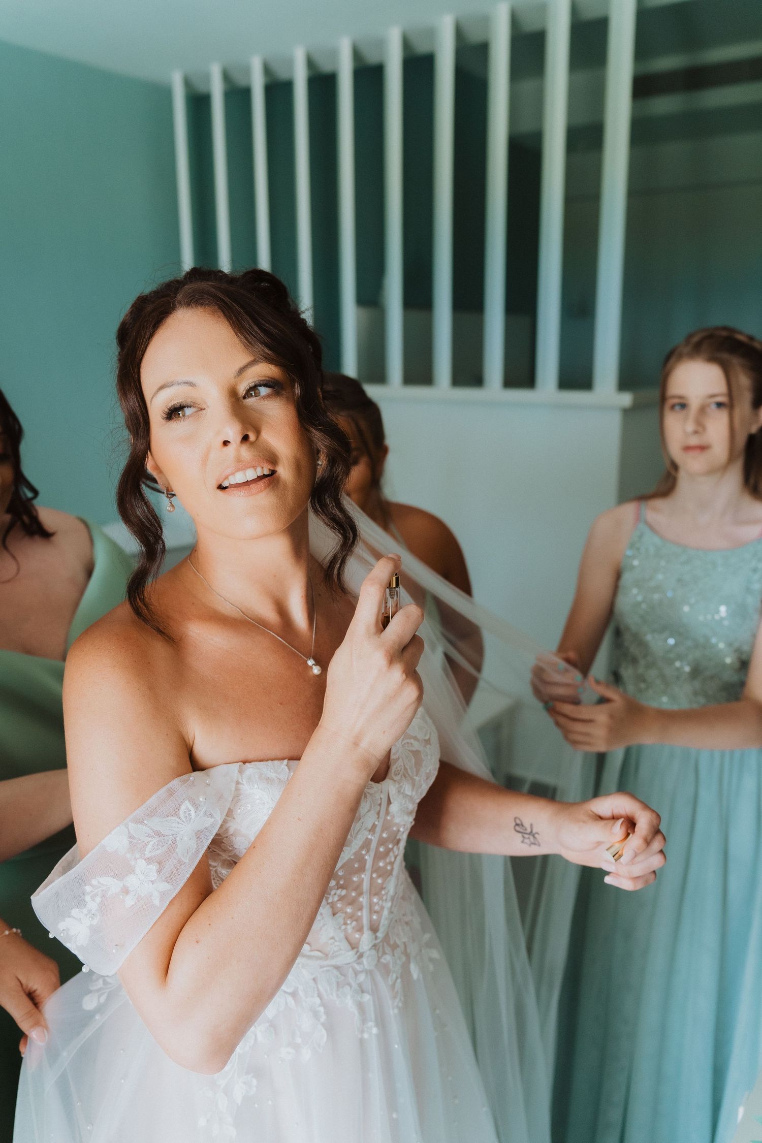 A candid moment of bridal preparations shows a bride in white lace getting ready while her bridesmaid wears mint green.