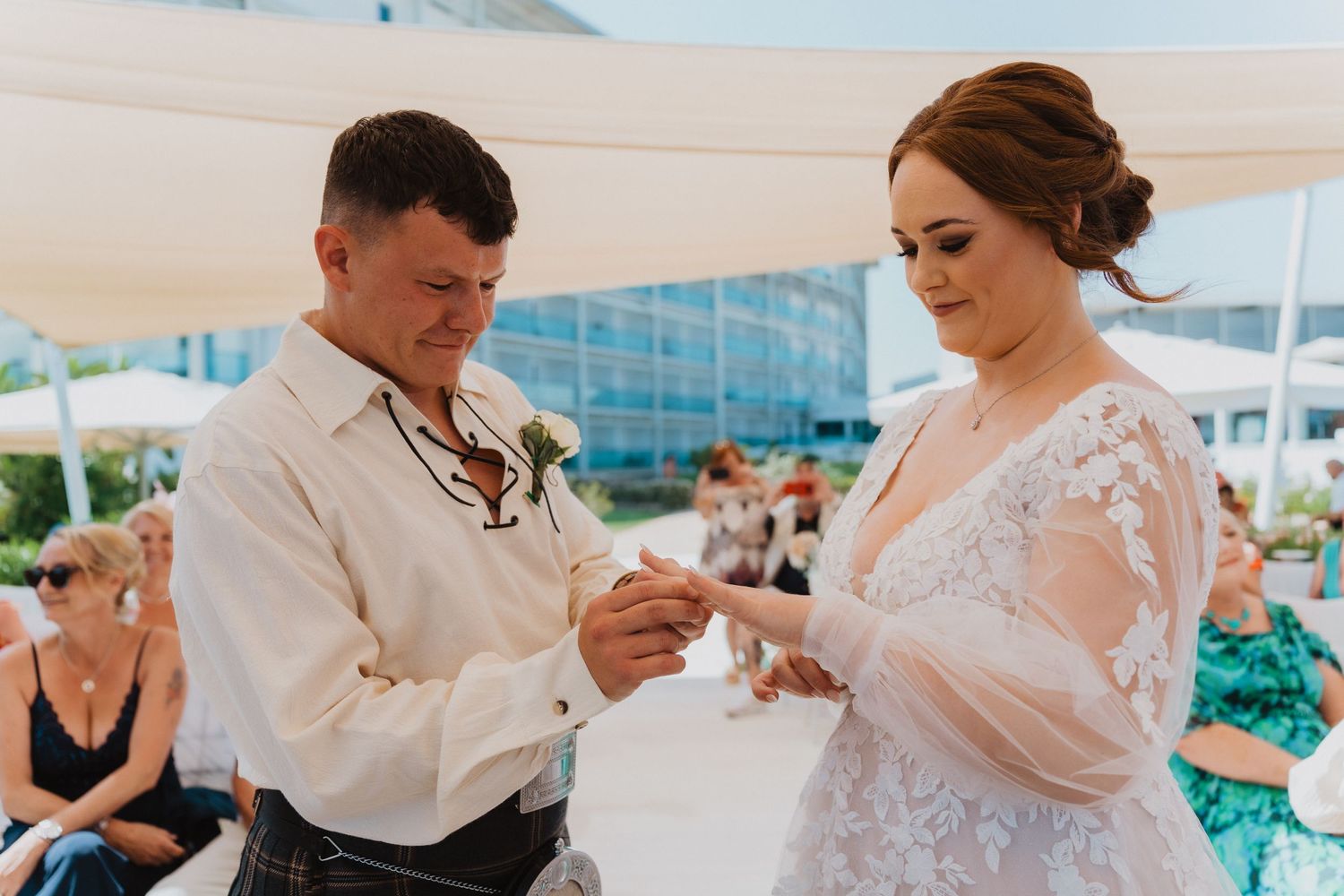 A couple reads their wedding vows during a beachside ceremony under a white tent.