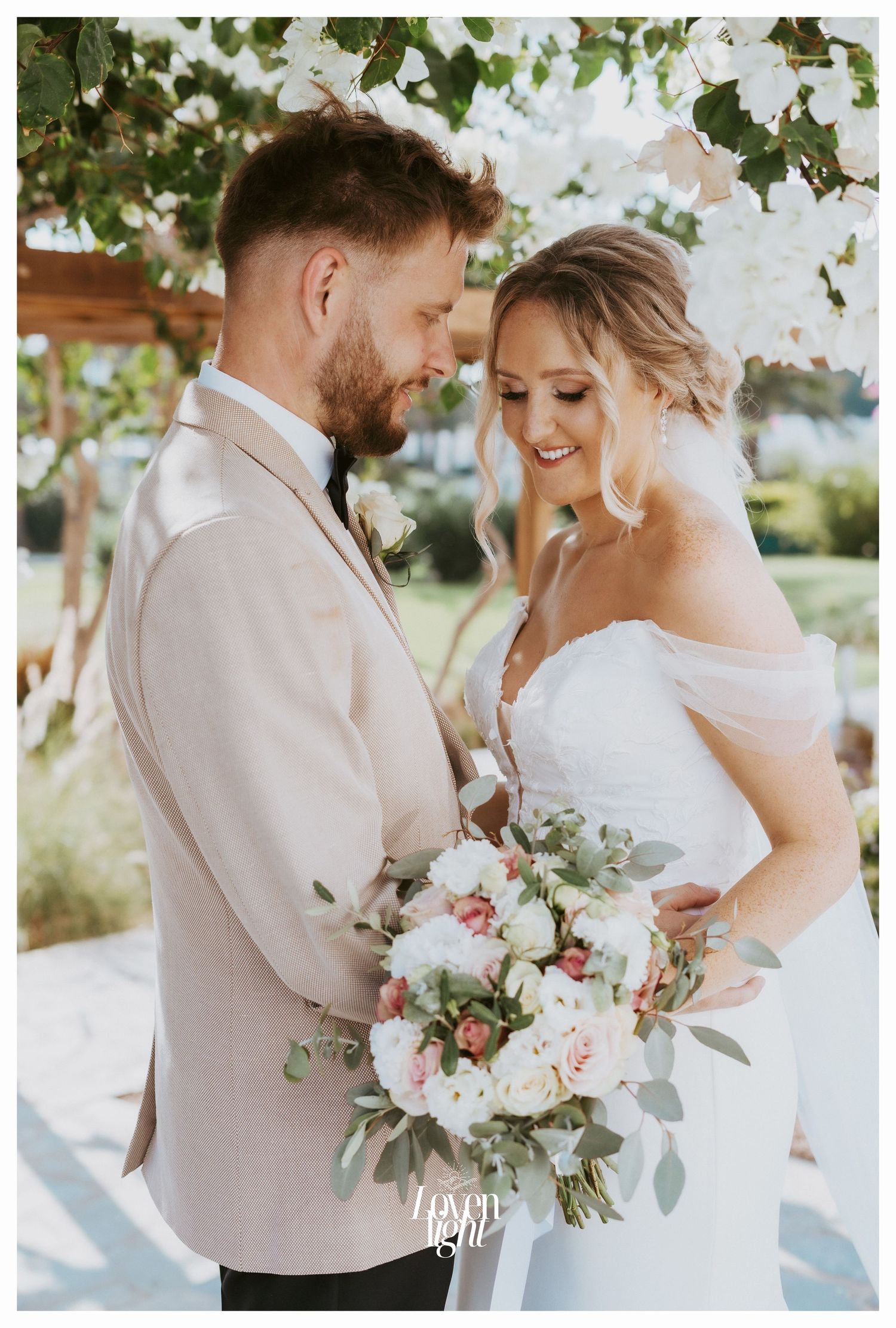 Romantic wedding moment captured under blooming trees with soft pink and white florals.