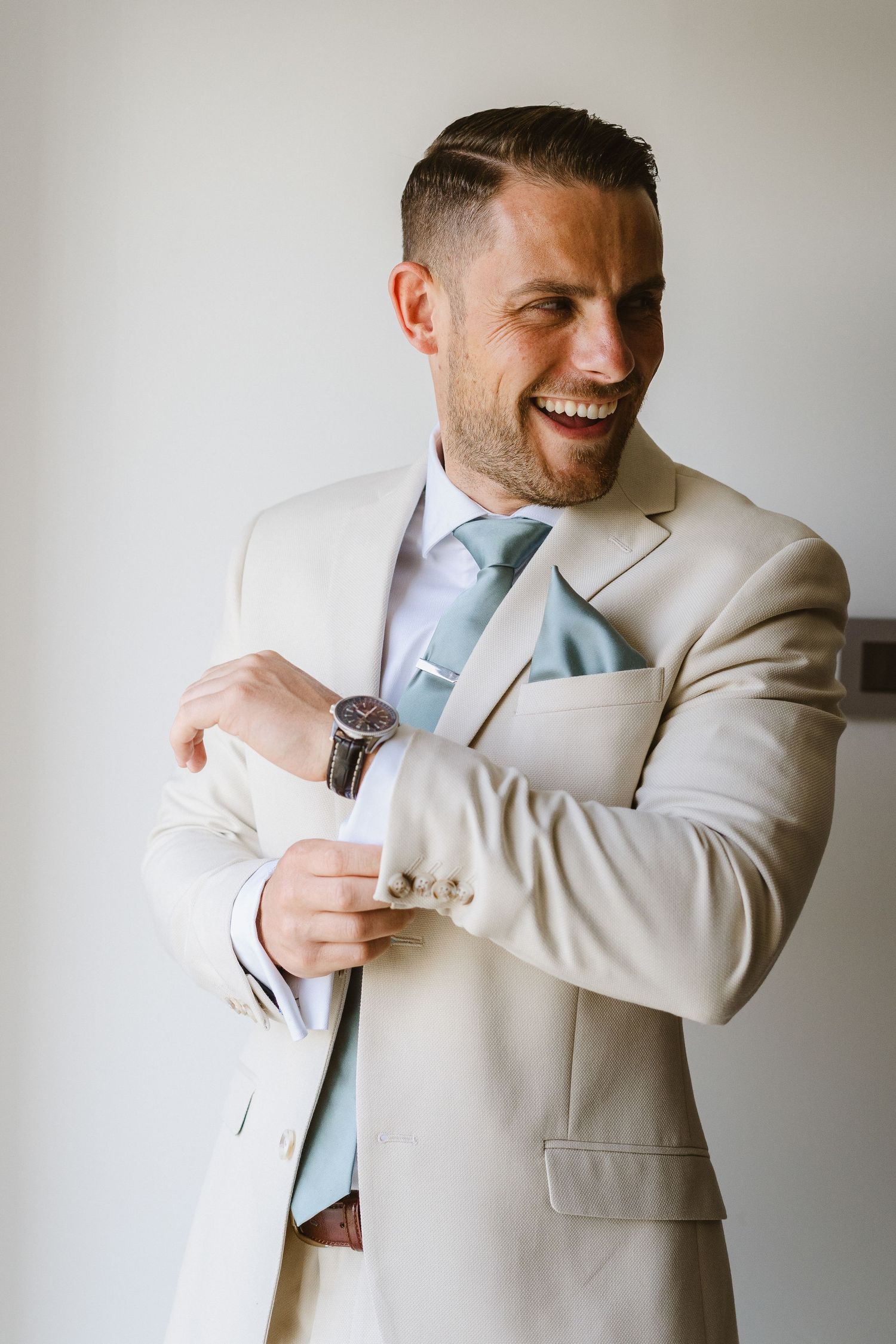 Candid portrait of someone in a light suit with blue tie smiling.