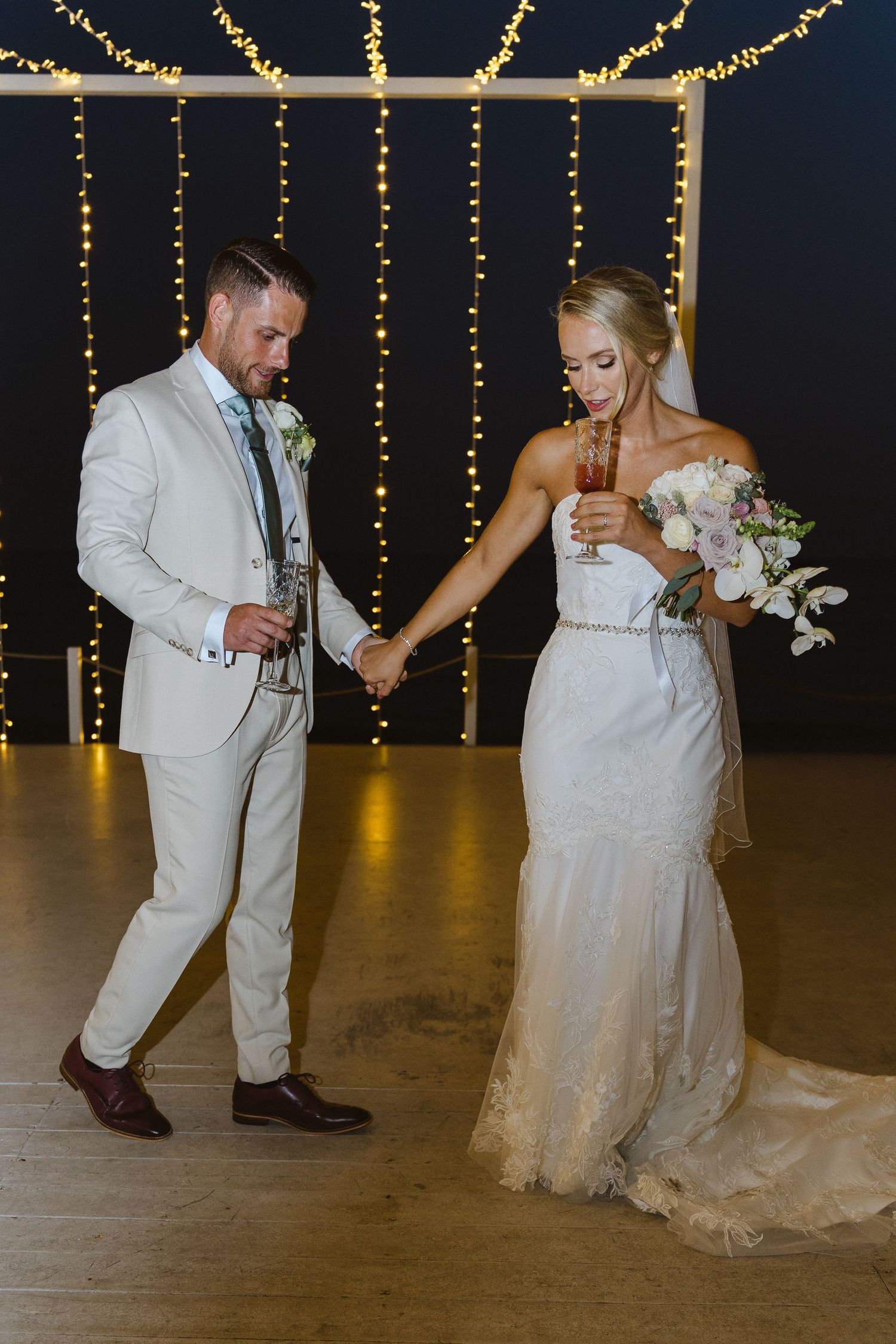 Bride and groom dance together on their wedding day under glowing fairy lights.