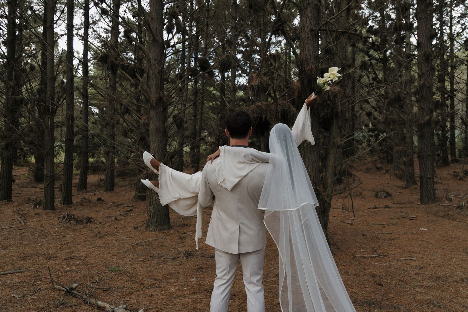 Groom carrying the bride in the forest just after they got married