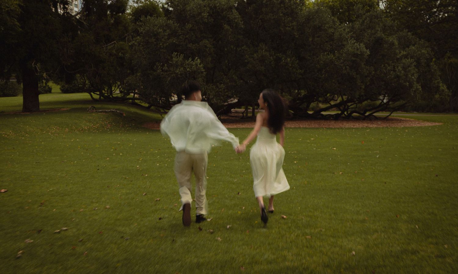 Couple running into the distance for their engagement shoot at the Auckland Domain