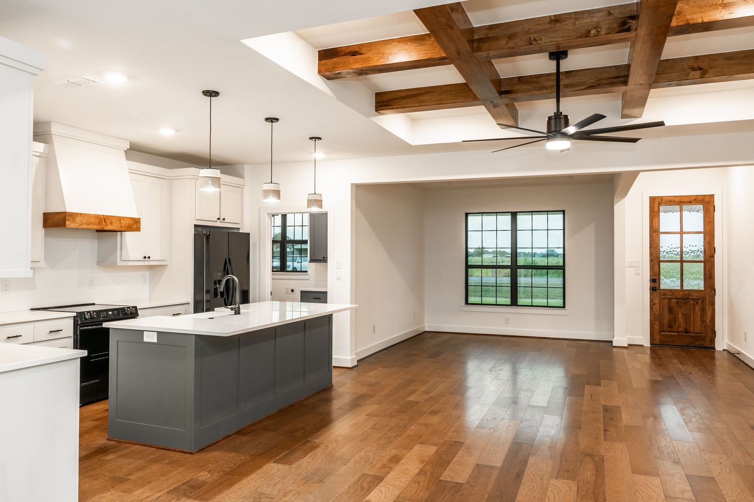 Open-concept kitchen with coffered wood ceiling, gray island, and hardwood floors.