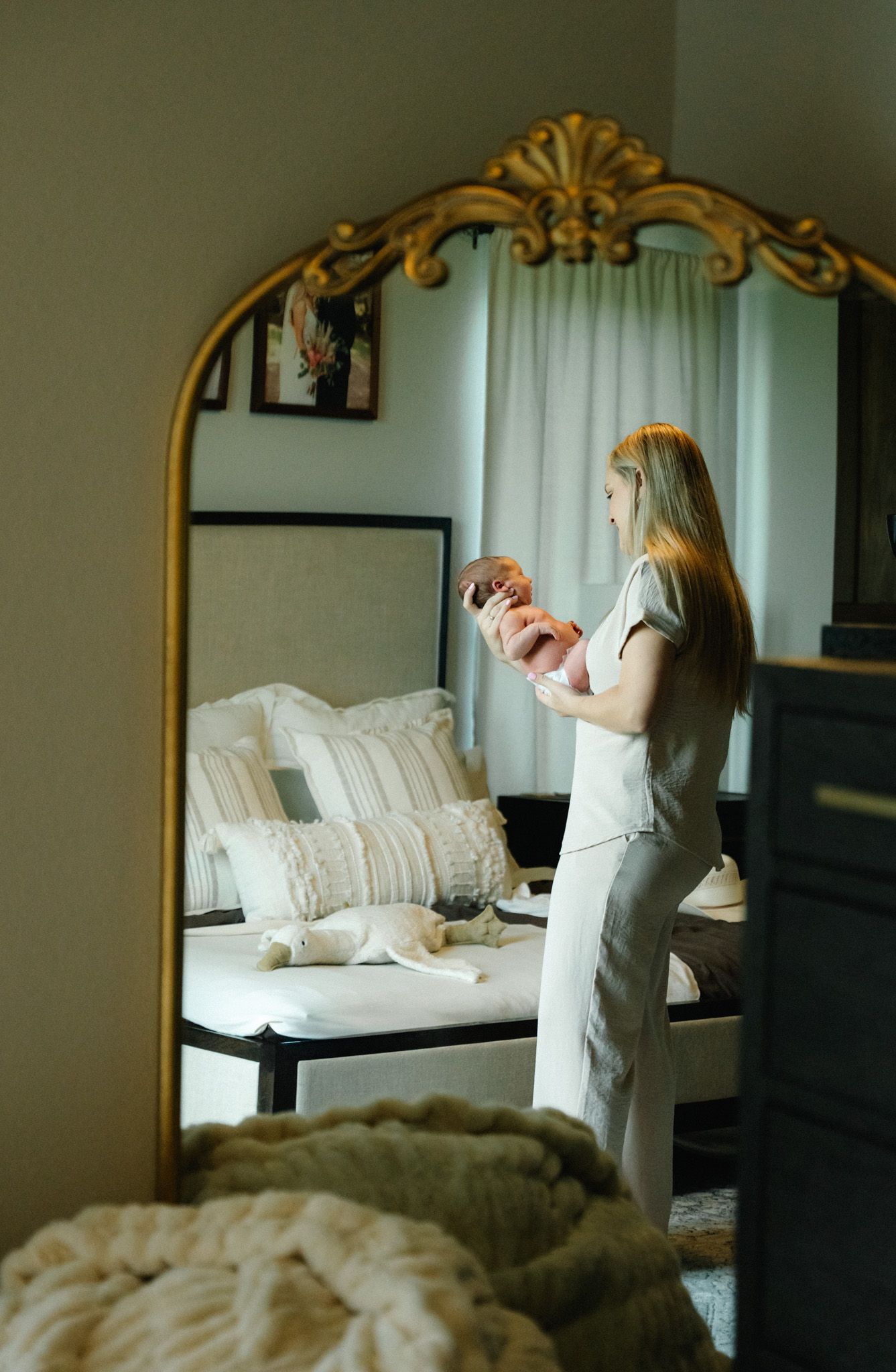 The reflection of a mother holding her newborn son in her bedroom.