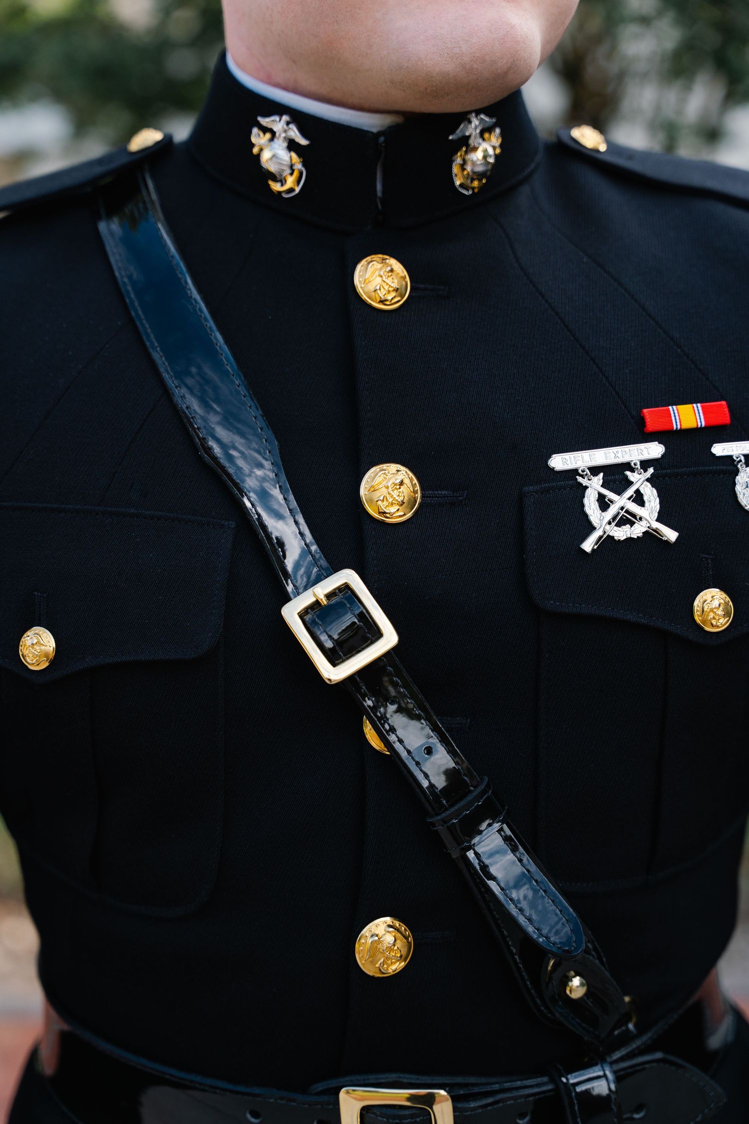 US Marine Corps dress blue uniform with gold buttons, medals, and black patent leather Sam Browne belt.