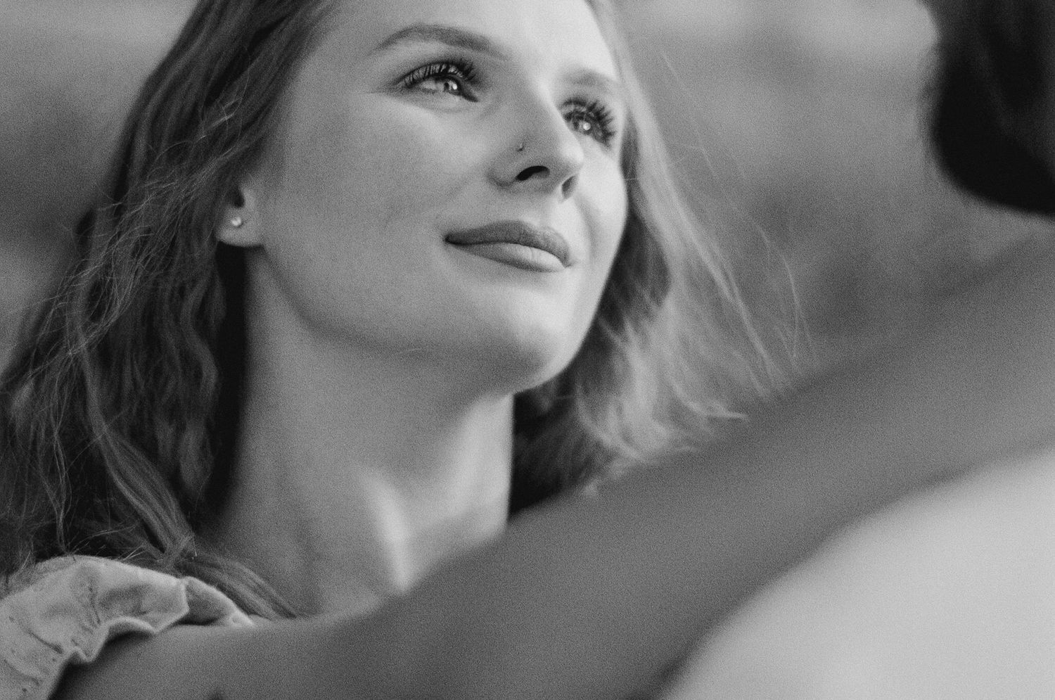 Black and white romantic portrait of a smiling woman gazing up tenderly at someone close to her.