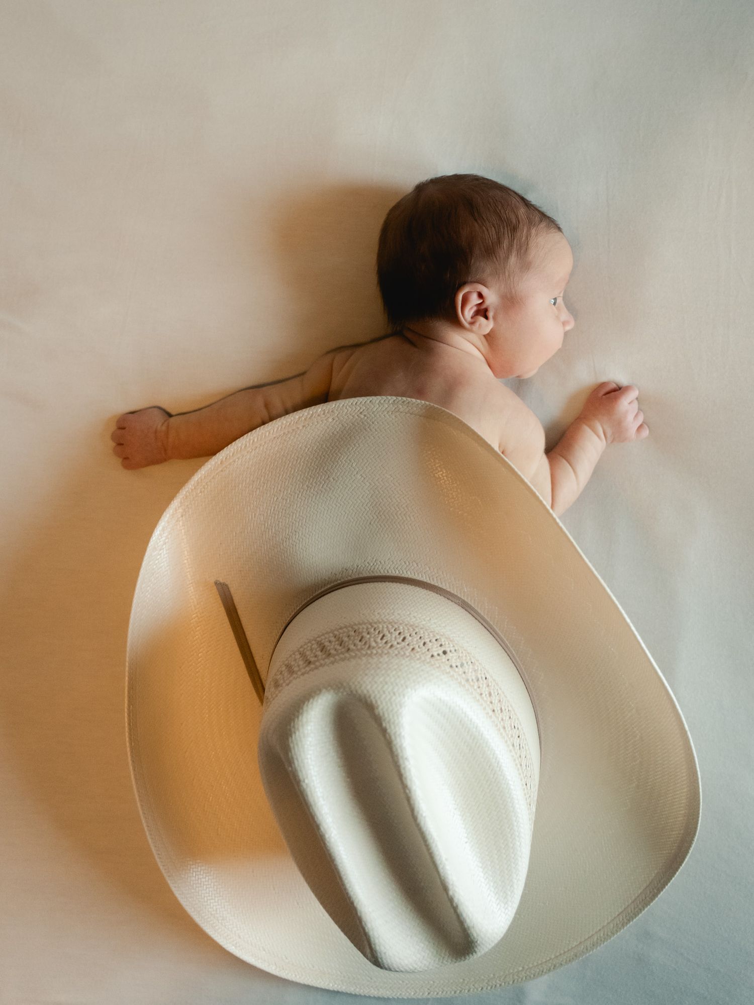 Newborn in-home session with a cowboy hat.
