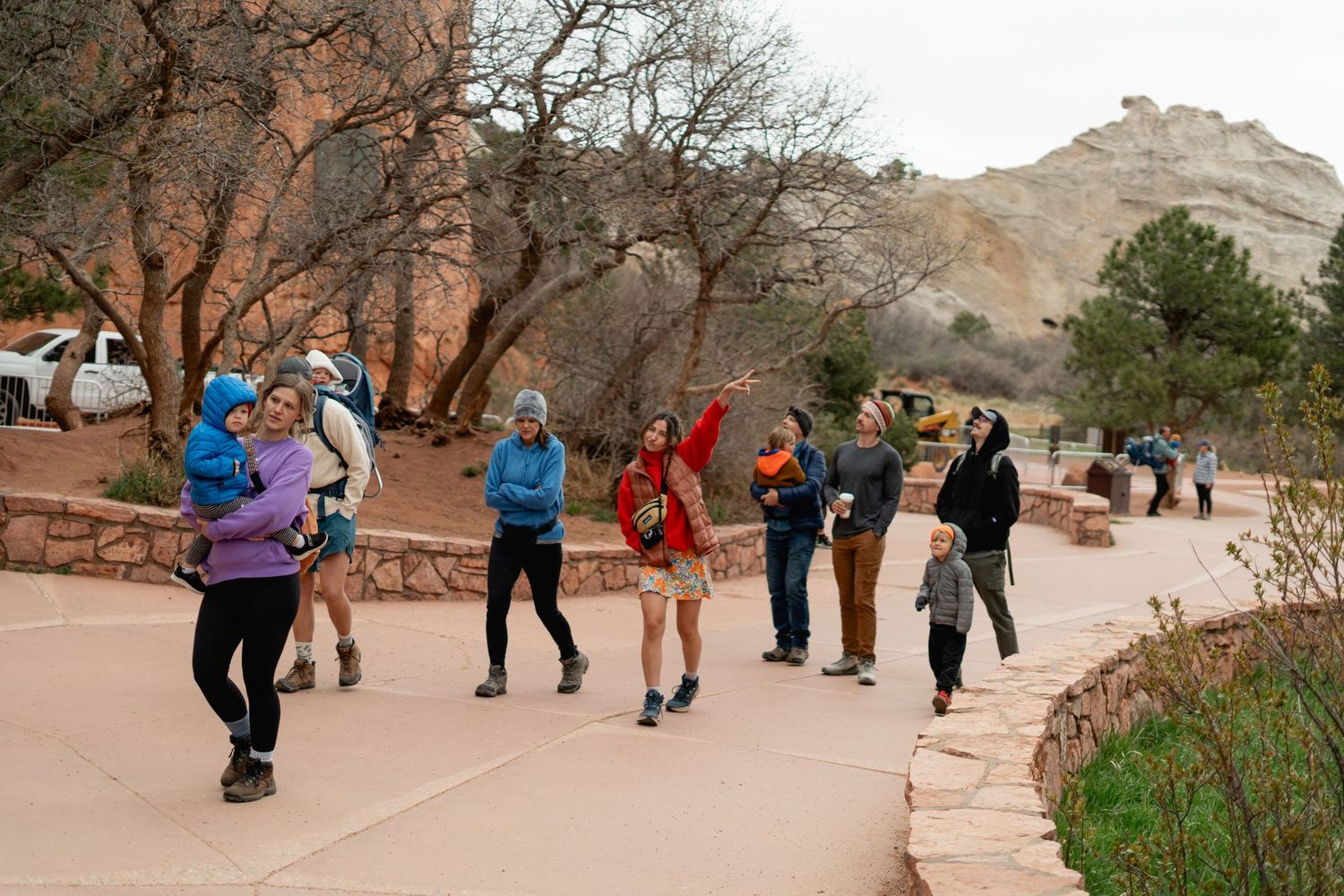 Group of hikers walking along a paved trail at a red rock canyon park on a cloudy day.