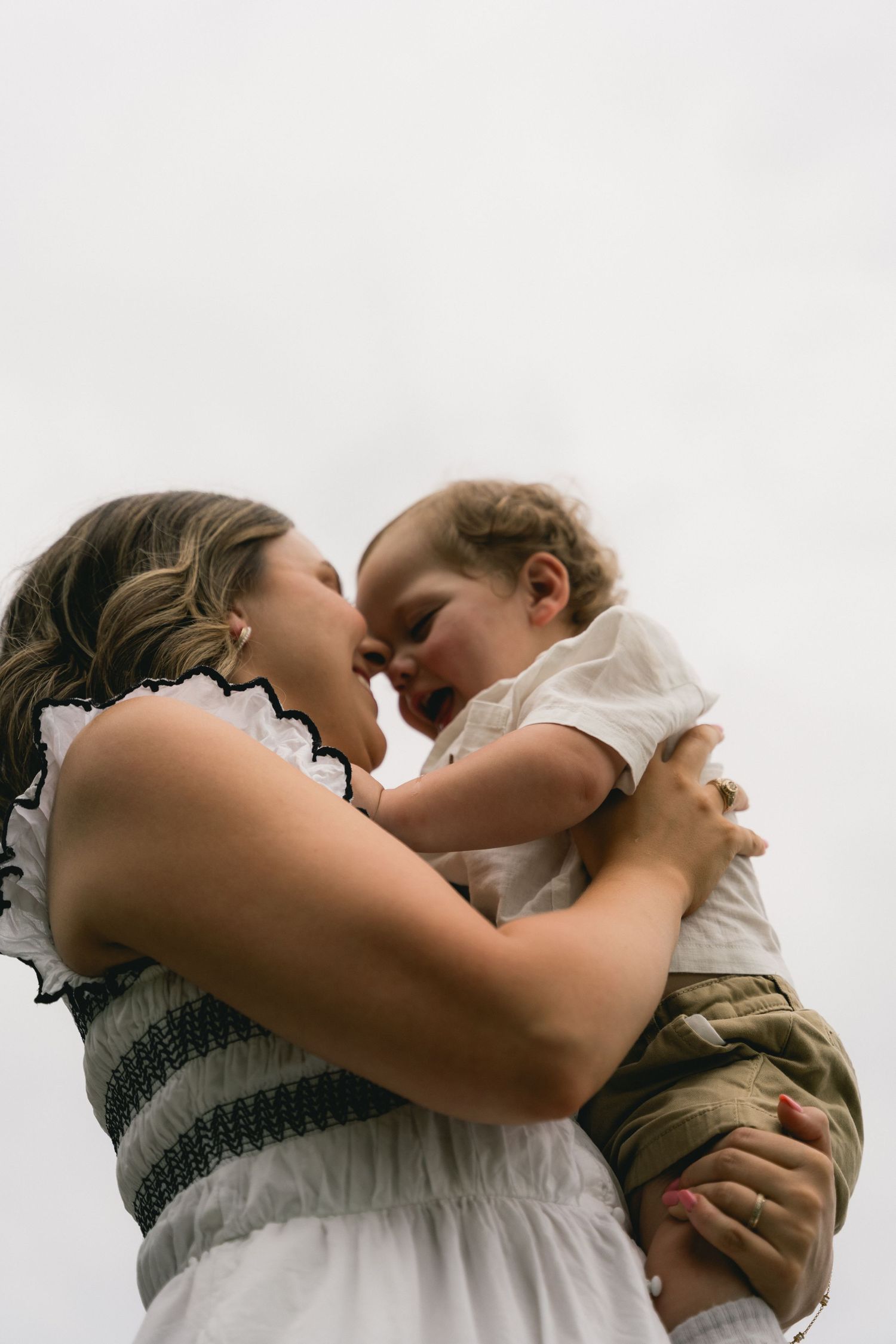 A joyful mother holds her laughing baby close, touching foreheads in a tender moment.