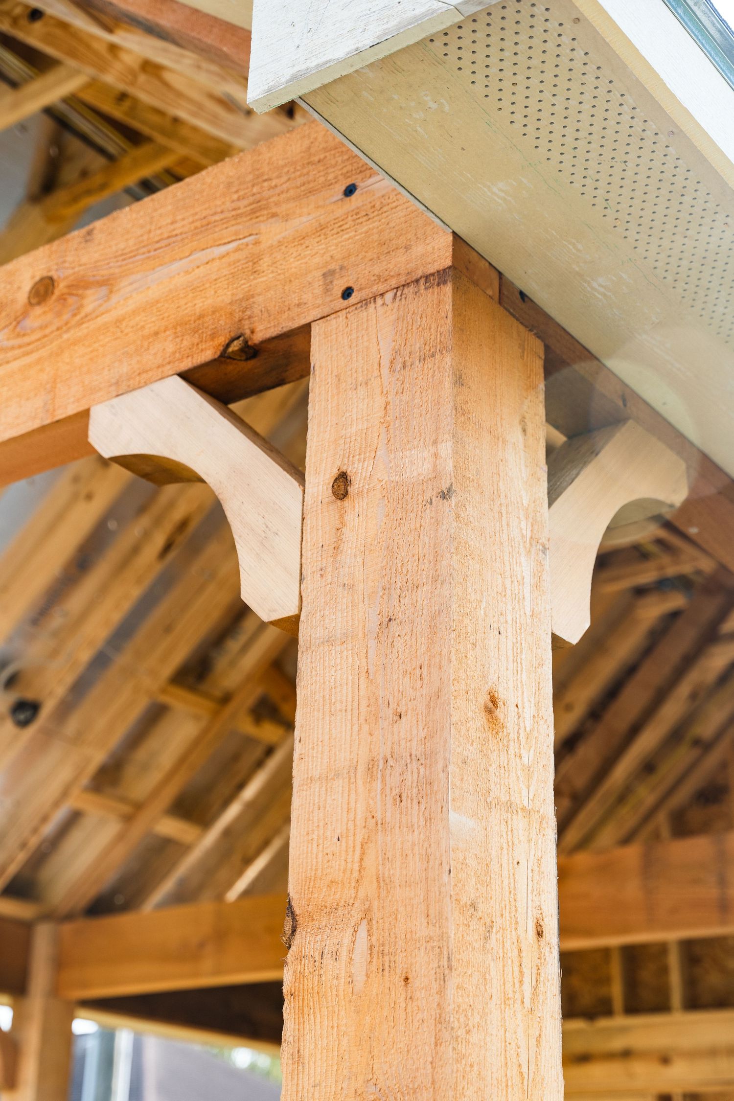 A decorative wooden post and beam bracket detail inside a timber frame home under construction.
