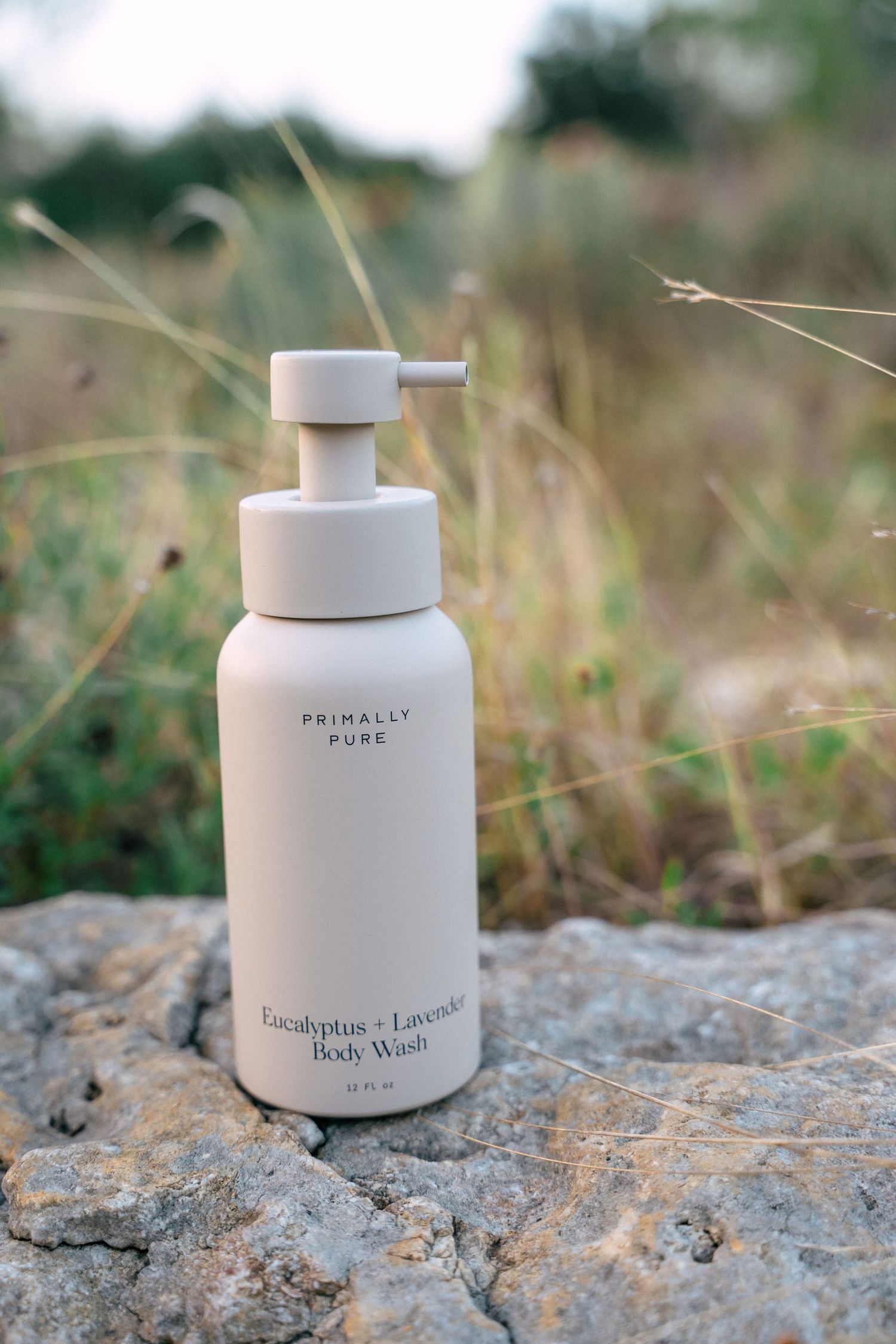 Primally Pure Eucalyptus and Lavender Body Wash pump bottle on a rock in a natural outdoor setting.