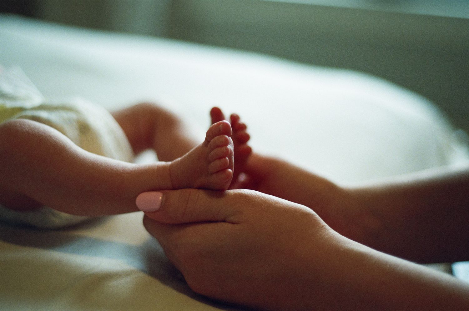 Mother holding her baby's little feet, taken on 35mm film photography.