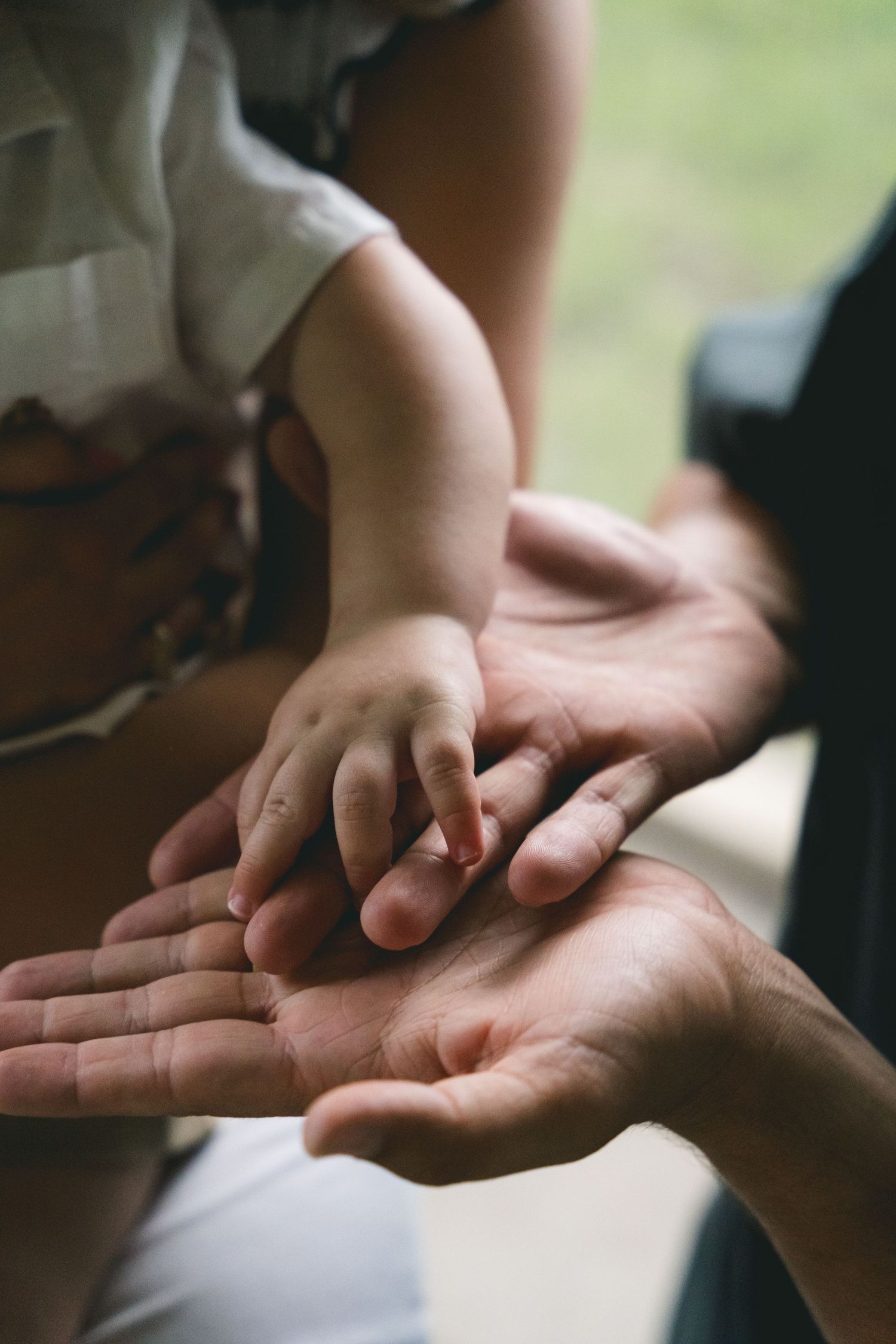Close-up of a baby's tiny hand resting gently on two adult hands in a tender moment.