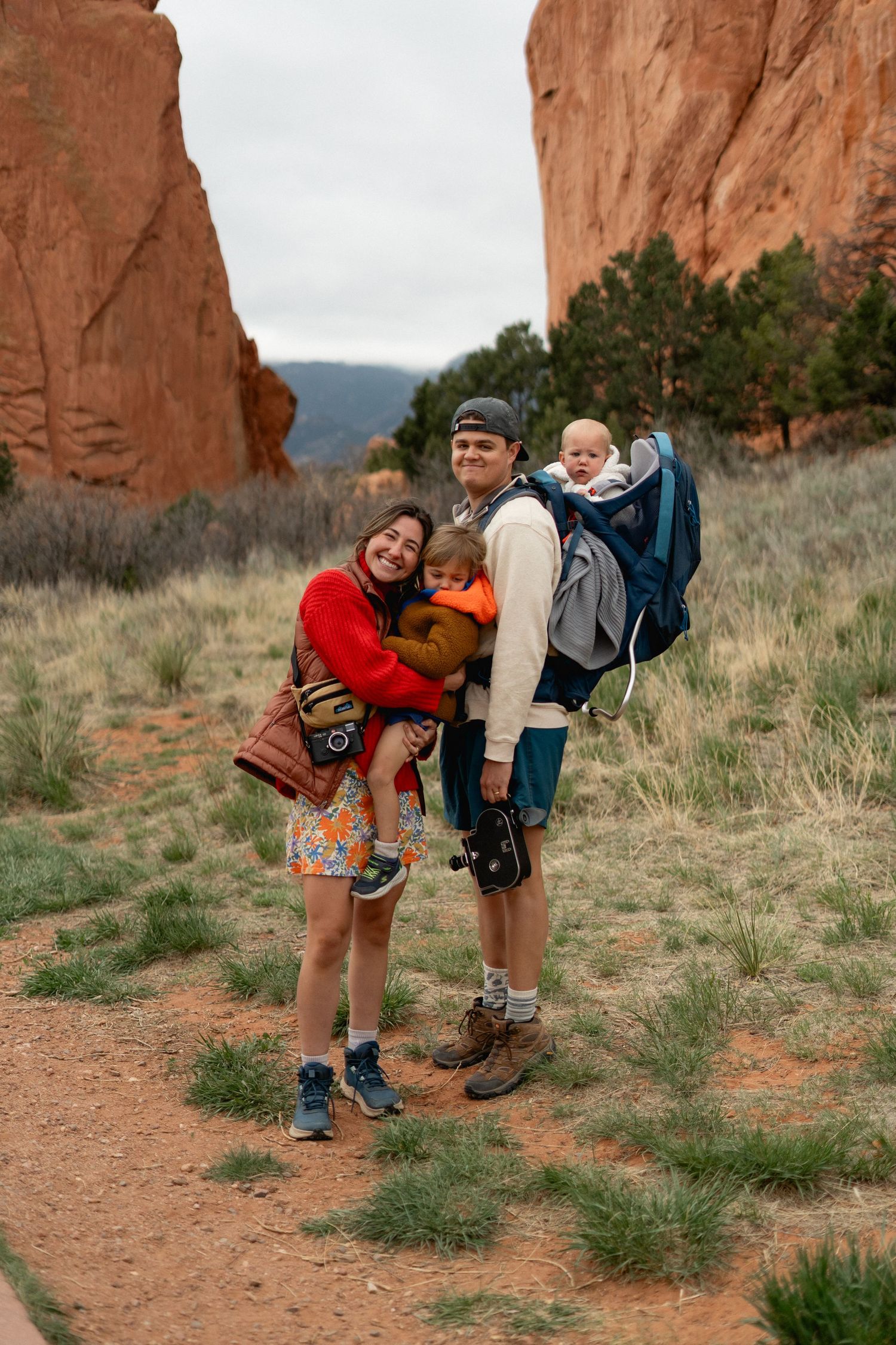 A young family with two small children poses on a trail surrounded by red rock formations at Garden of the Gods.