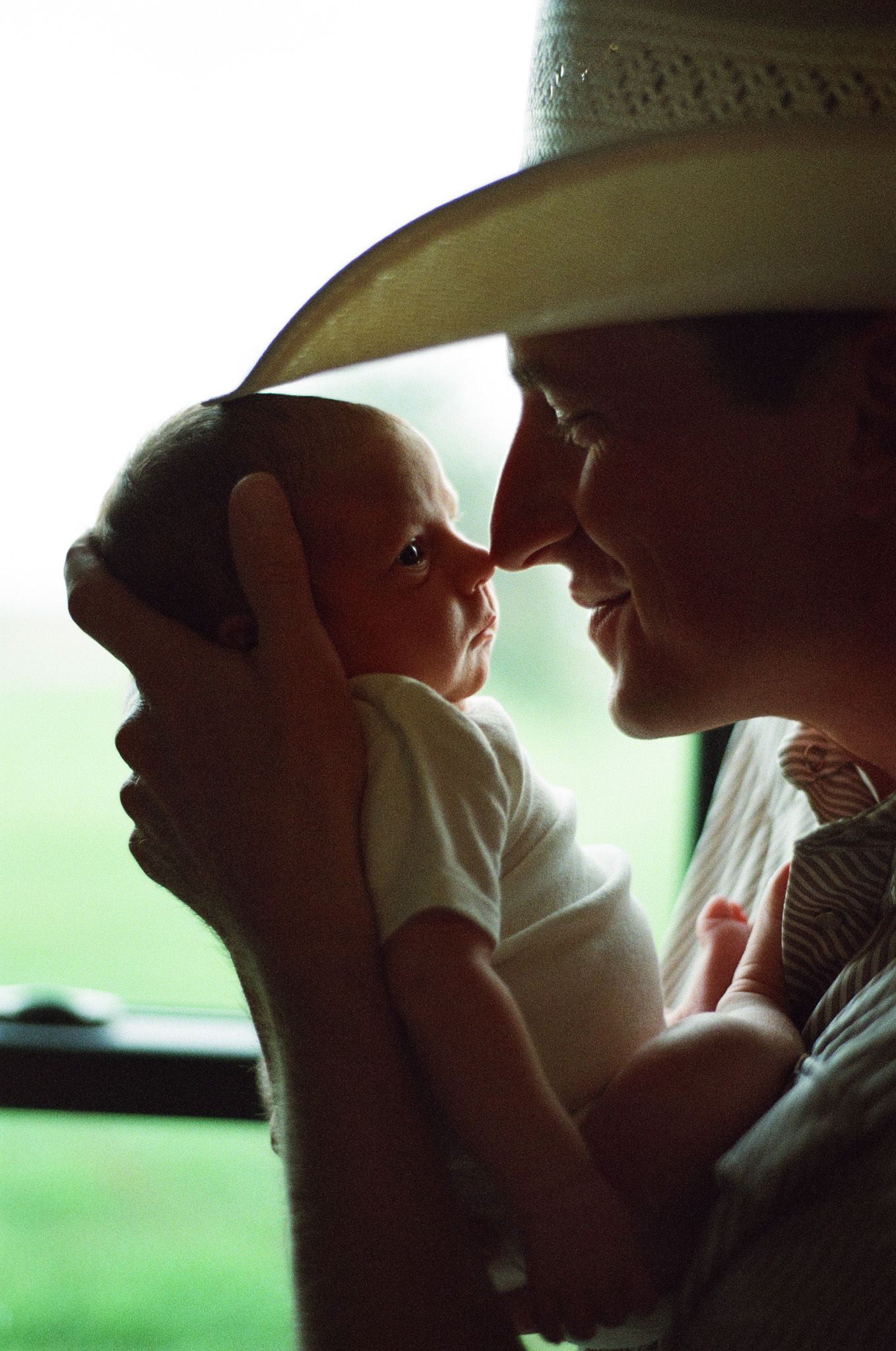 Father touching noses with his newborn son, taken on 35mm film photography.