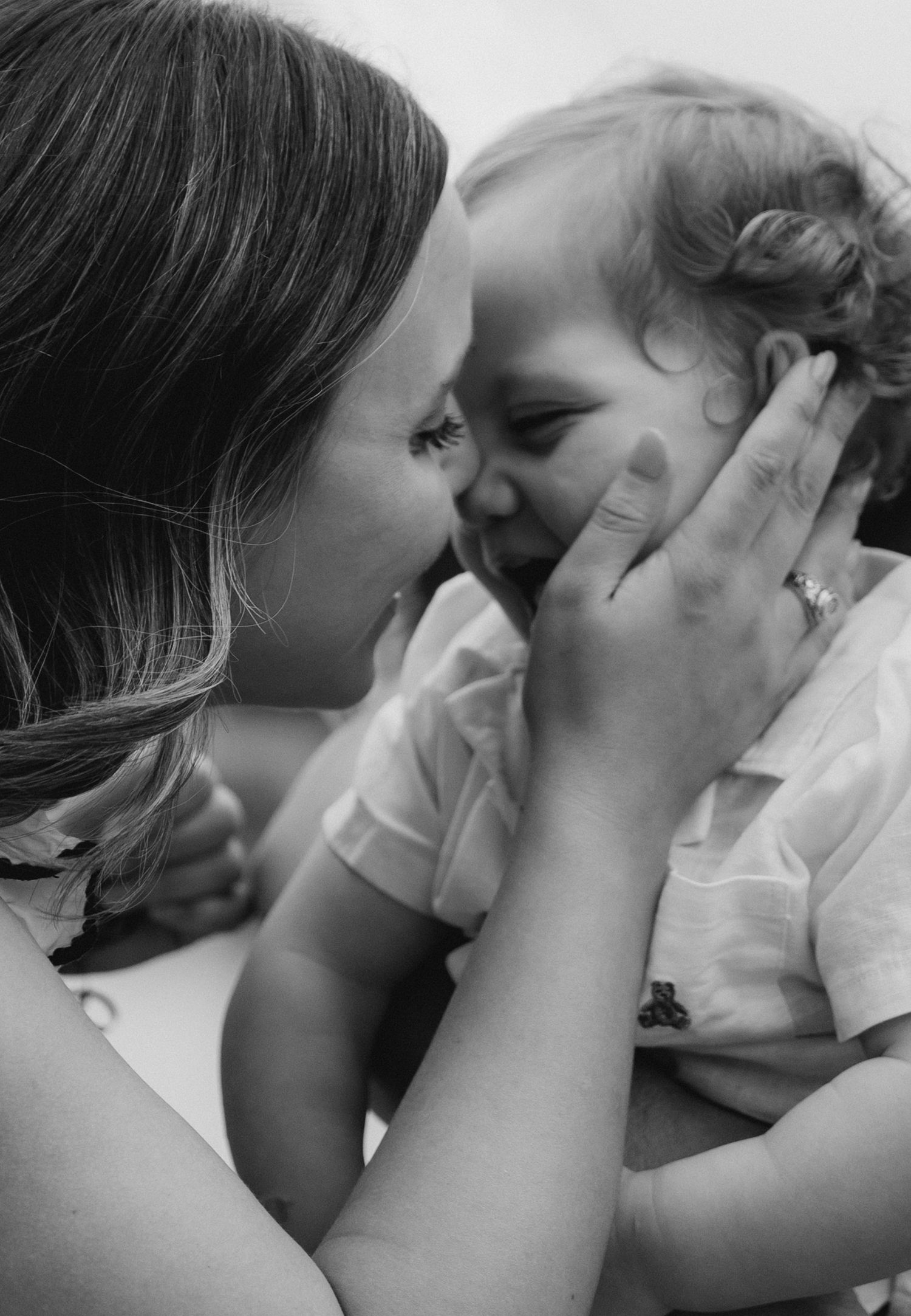 A black and white portrait of a smiling mother tenderly holding her giggling baby close.