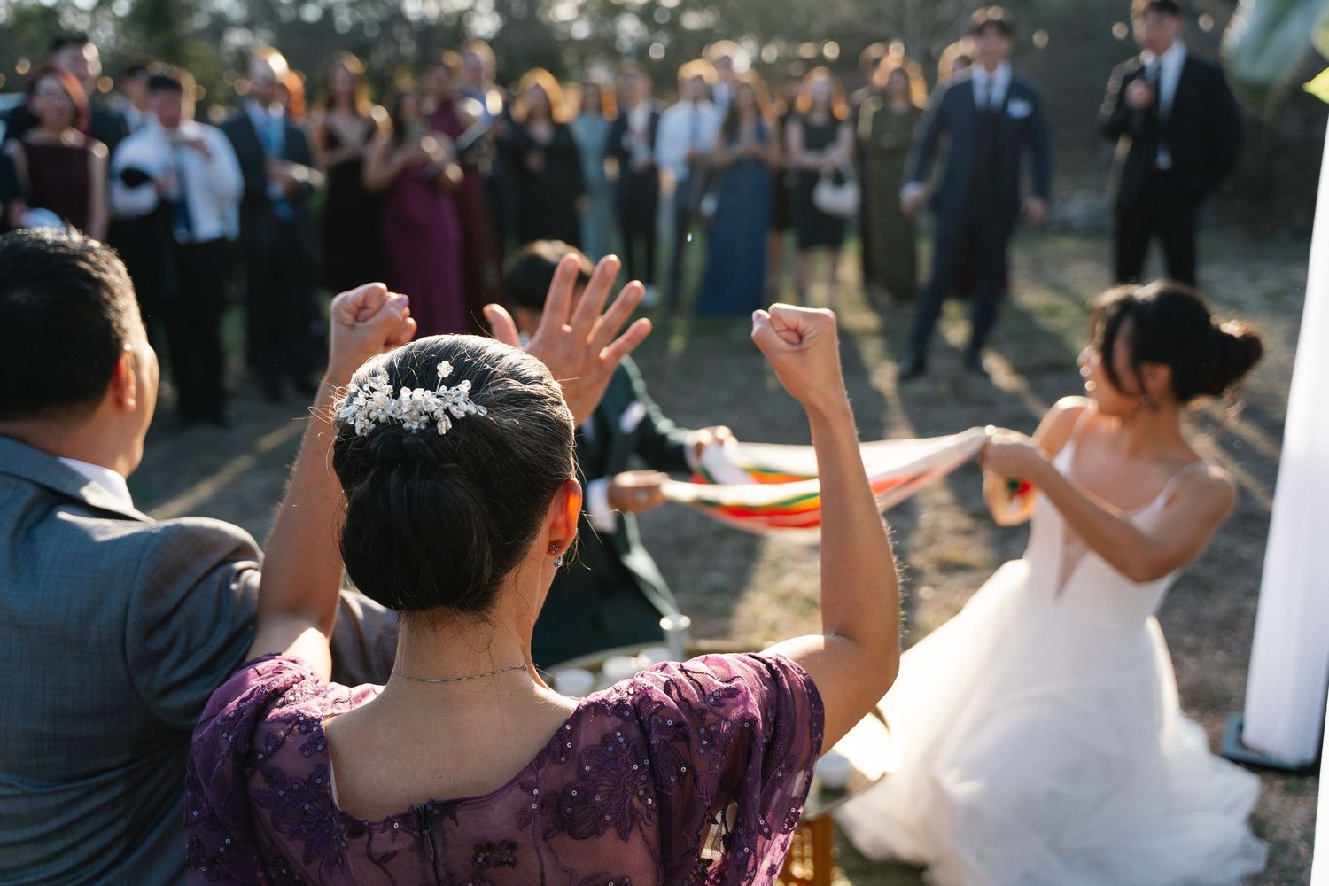 Guests cheering and celebrating as bride dances at outdoor wedding reception.