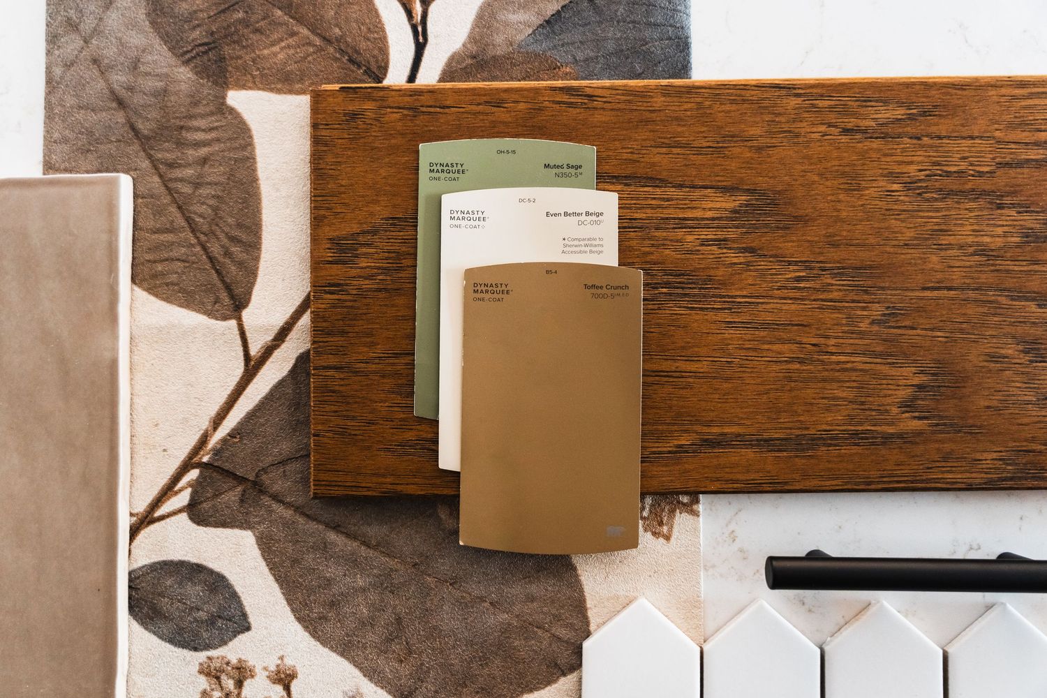 A flat lay of wood, tile, and fabric material samples with paint swatches on a neutral background.