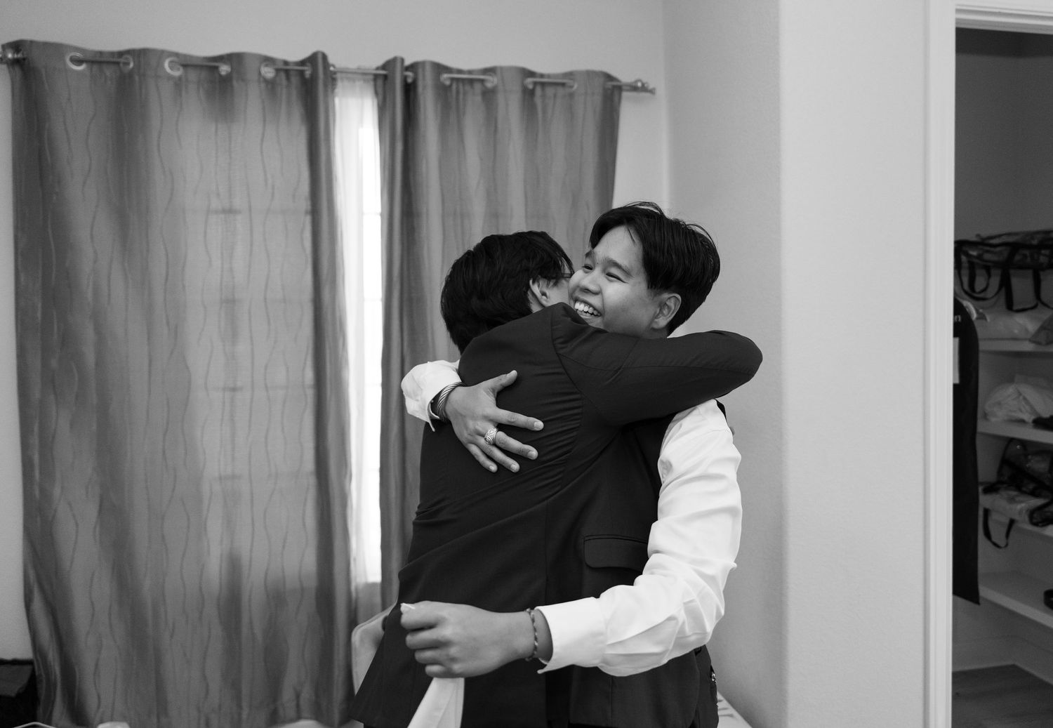 Two men sharing an emotional hug in a black and white wedding photo.