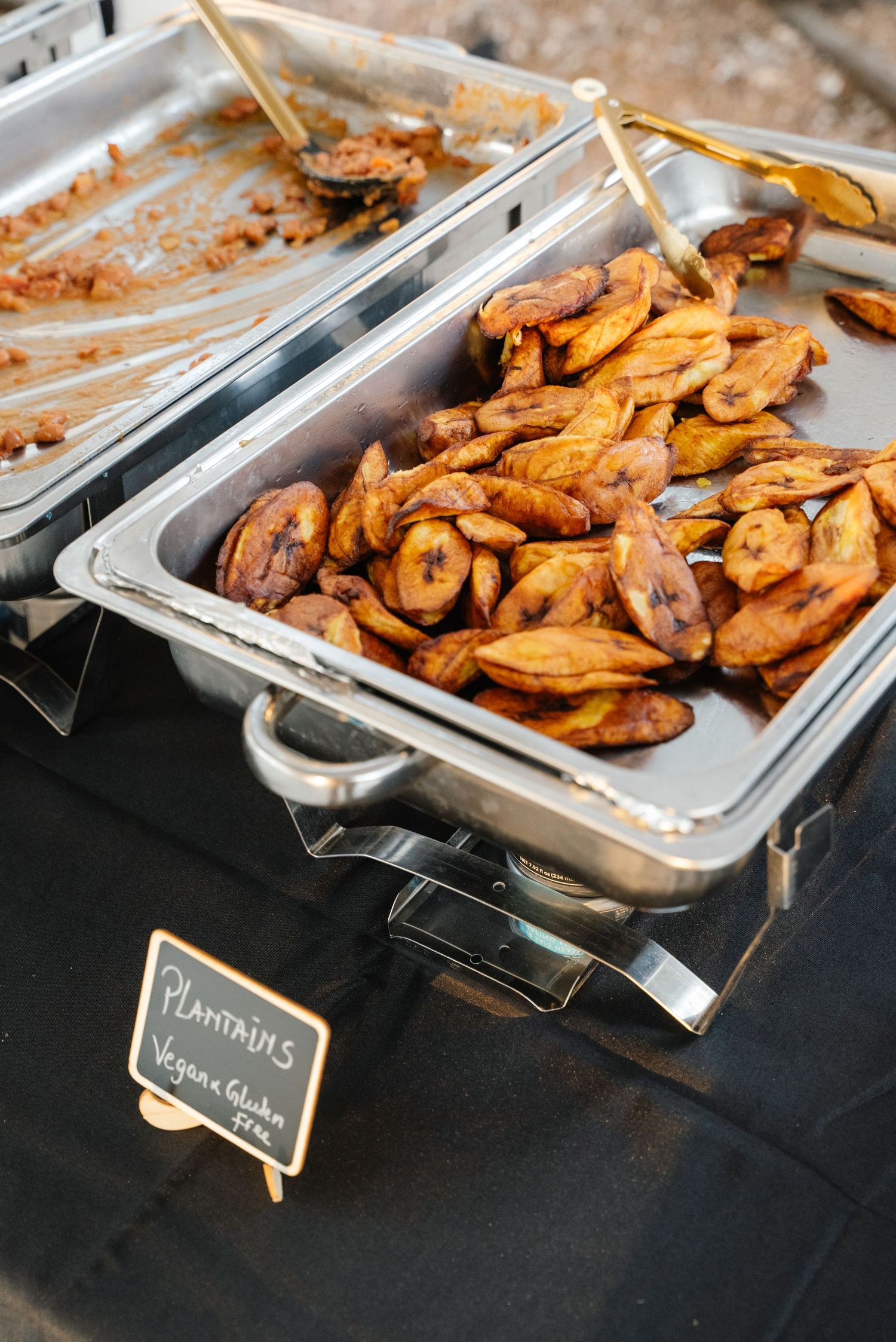 Catering tray of fried plantains labeled vegan and gluten-free at wedding reception buffet.