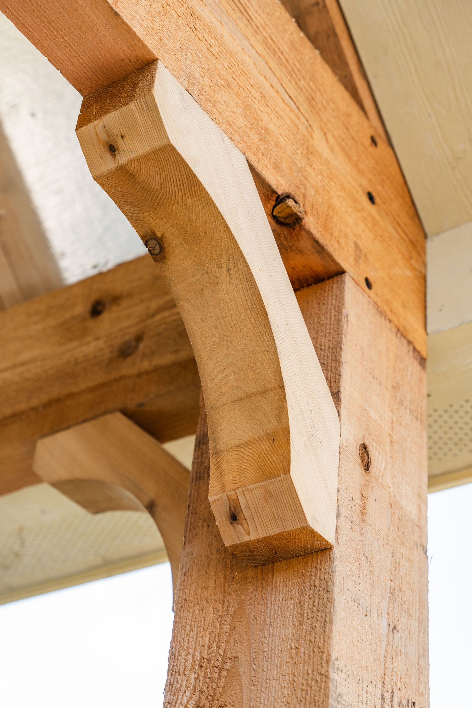 Close-up of a decorative wooden corbel supporting a rustic timber beam on a porch.