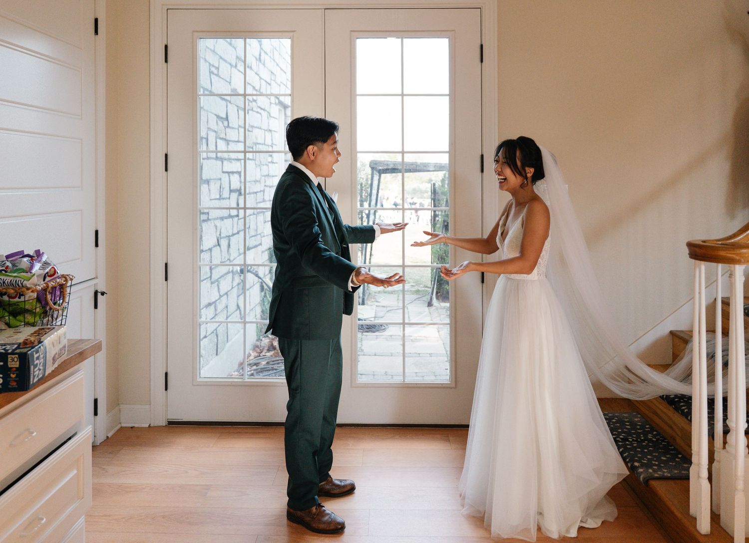 Bride and groom sharing emotional first look moment inside bright foyer.