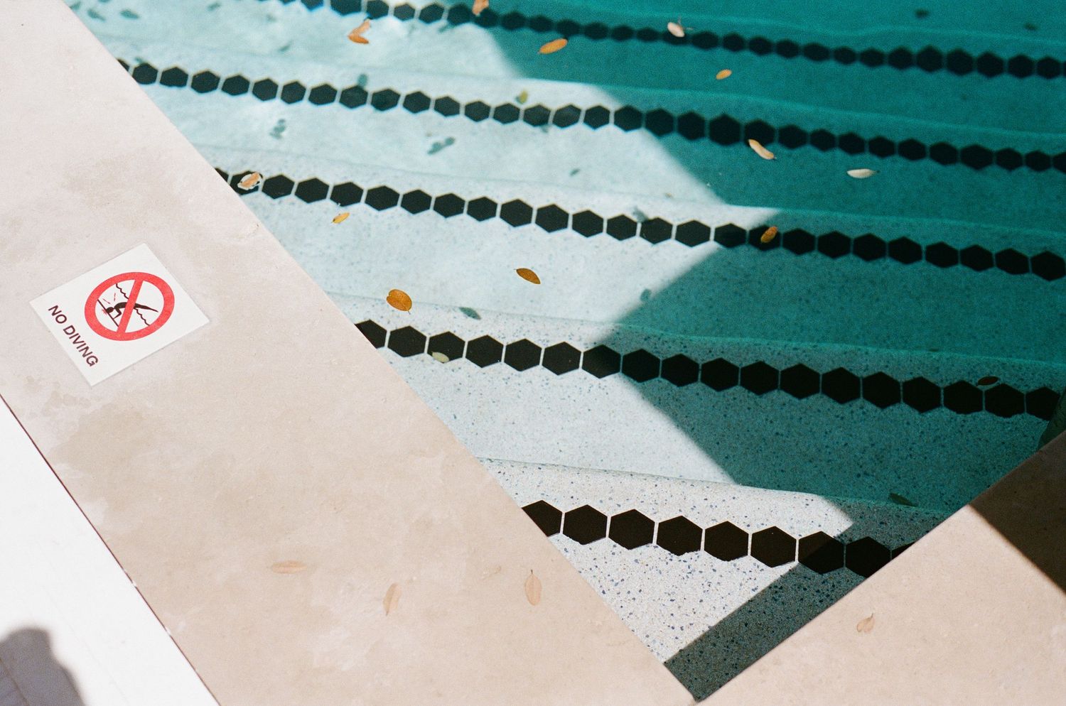 Aerial view of an outdoor swimming pool with lane dividers and a no diving sign on the pool deck.